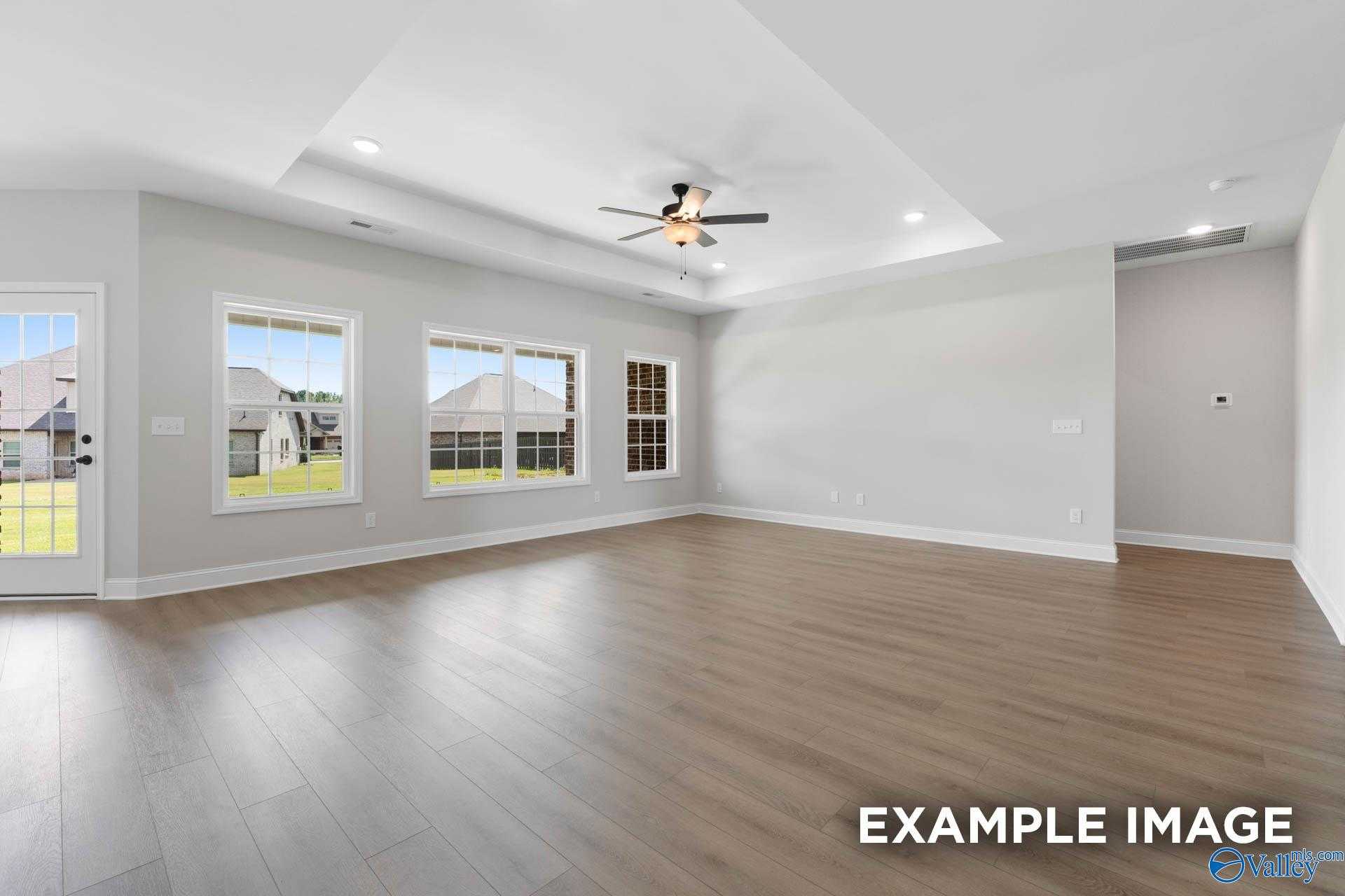 Spacious open living room with hardwood floors, large windows to yard, and ceiling fan in Davidson Homes The Rockford, Decatur, Alabama