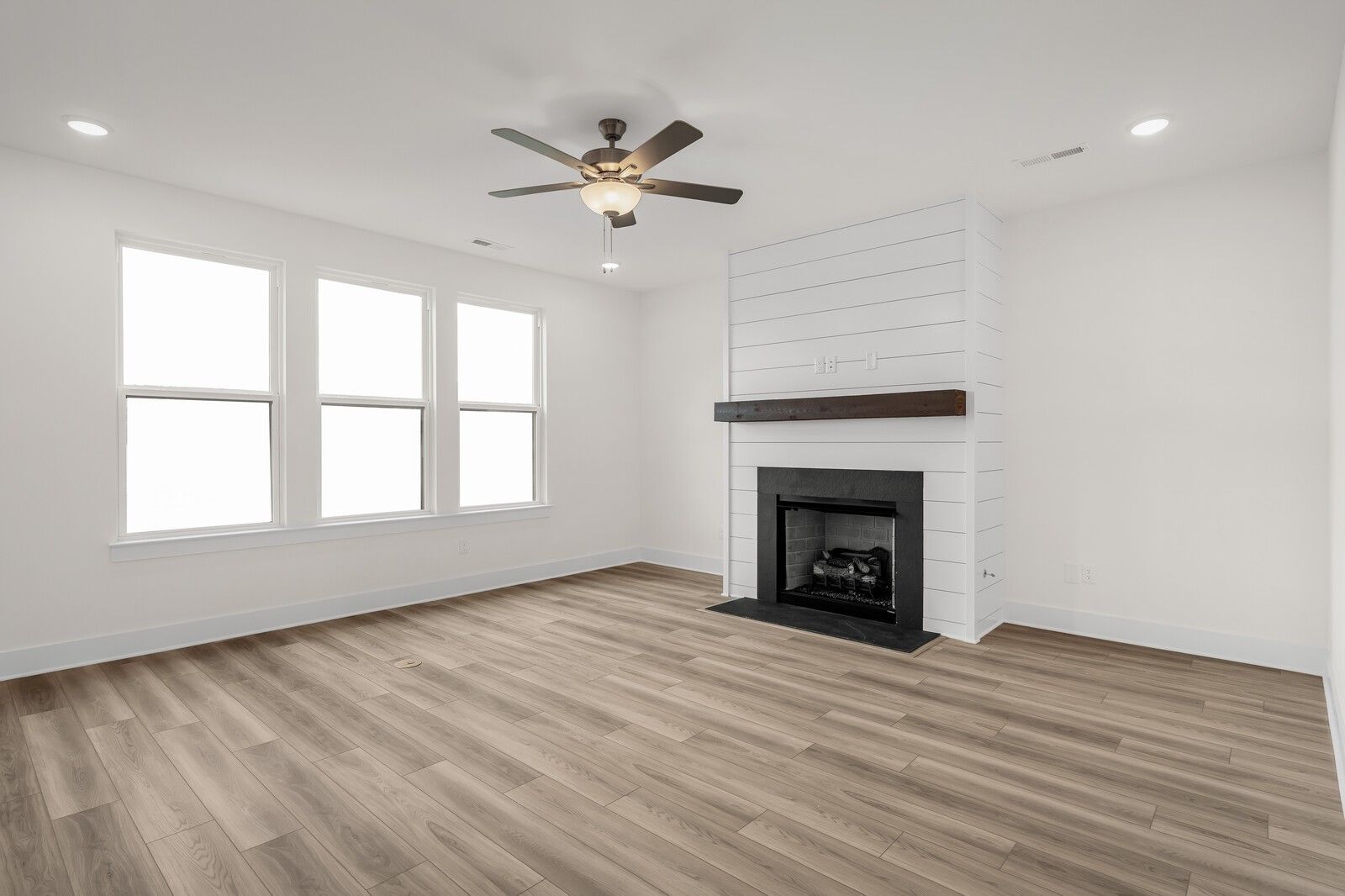Living room with white shiplap fireplace, wood mantel, and hardwood floors in The Henry C floor plan, Mt. Juliet, Tennessee.