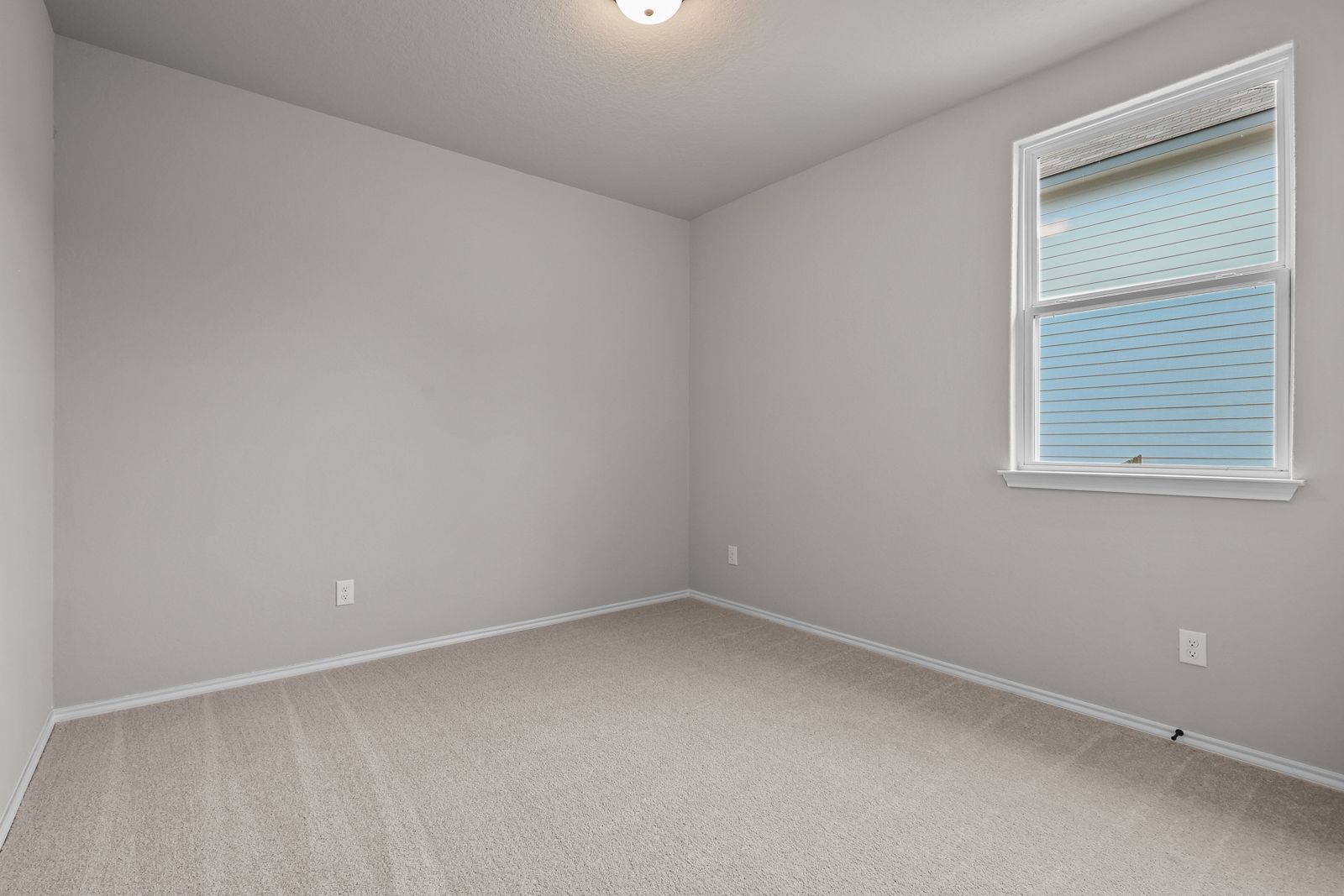 Spacious secondary bedroom with neutral carpet and walls in The Glenwood E floor plan by Davidson Homes in Seguin, Texas.