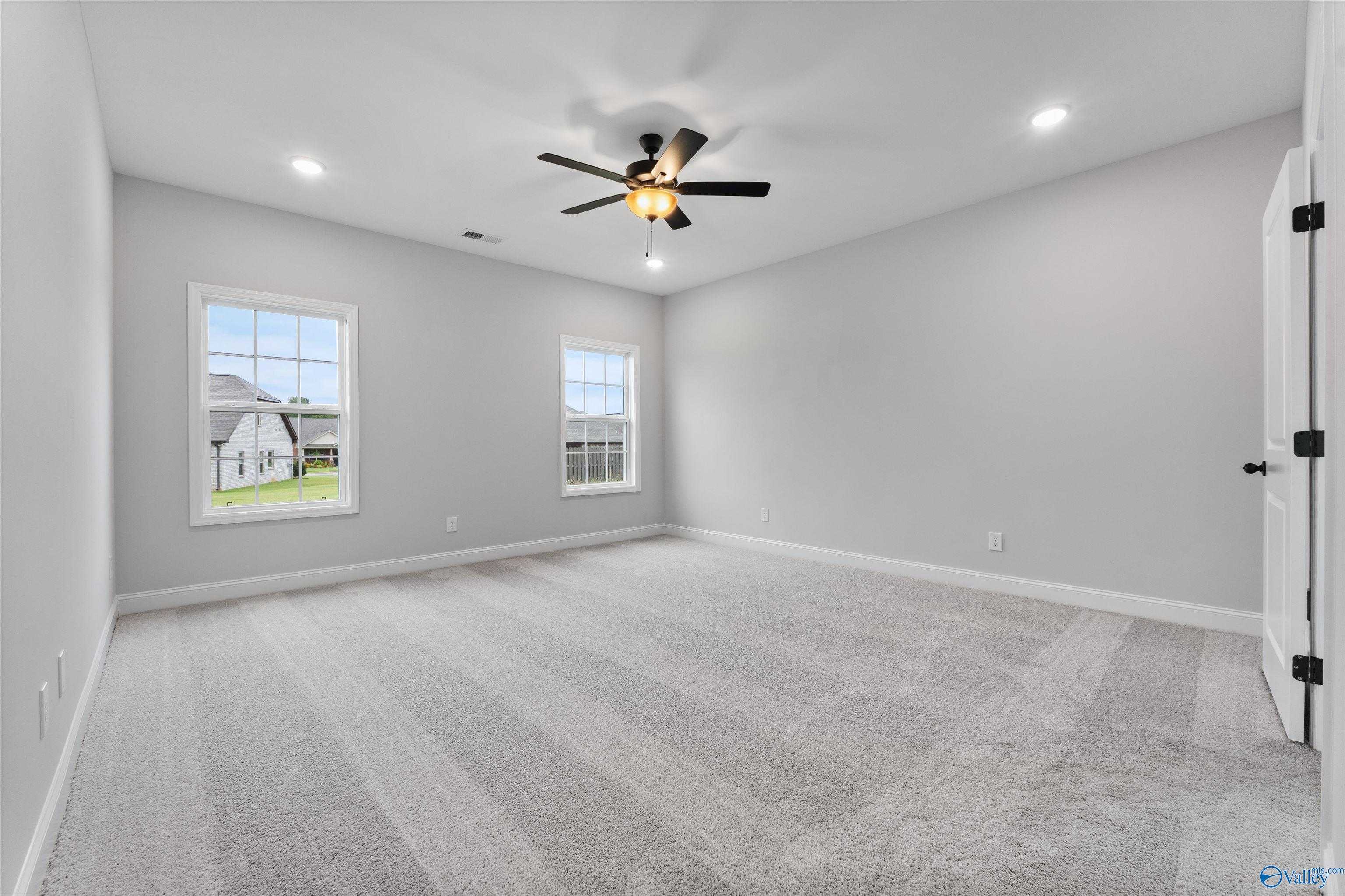 Bright secondary bedroom with light gray walls, plush carpet, double windows, and ceiling fan in Davidson Homes The Rockford, Toney, Alabama
