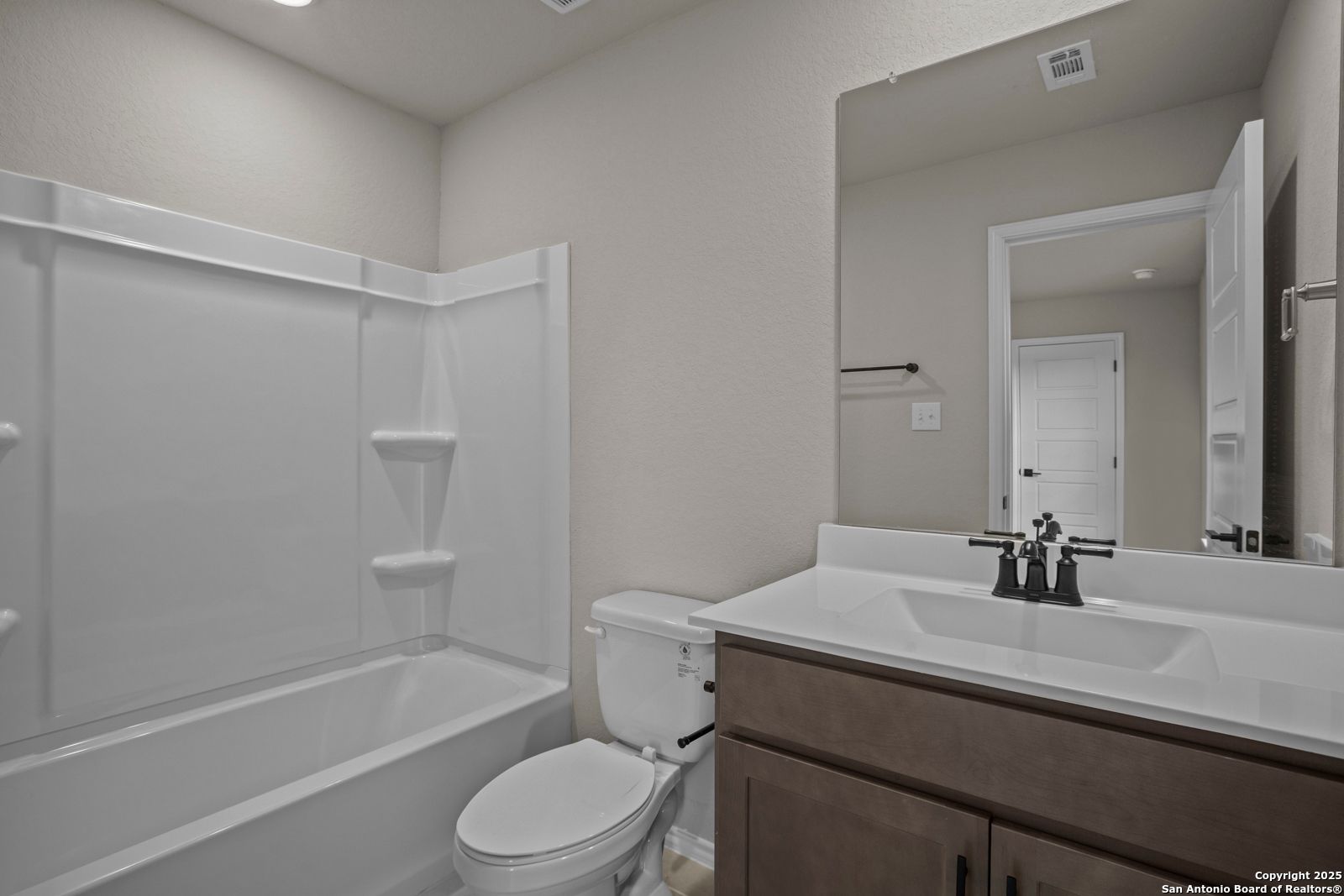 Modern guest bathroom with tub-shower combo, single vanity sink, mirror, and neutral walls in Davidson Homes The Douglas F, San Antonio