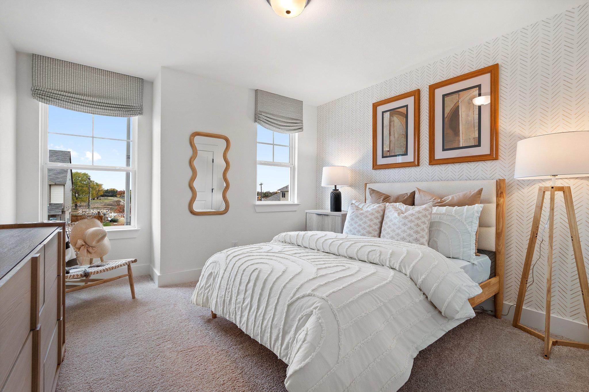 Spacious master bedroom in The Wake C featuring white tufted bed, large windows with gray curtains, and modern neutral decor