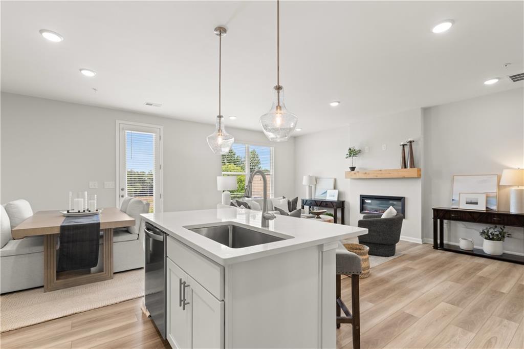 Open-concept kitchen and living area with island and fireplace in The Wake B floor plan at Hemingway, Cumming, Georgia.