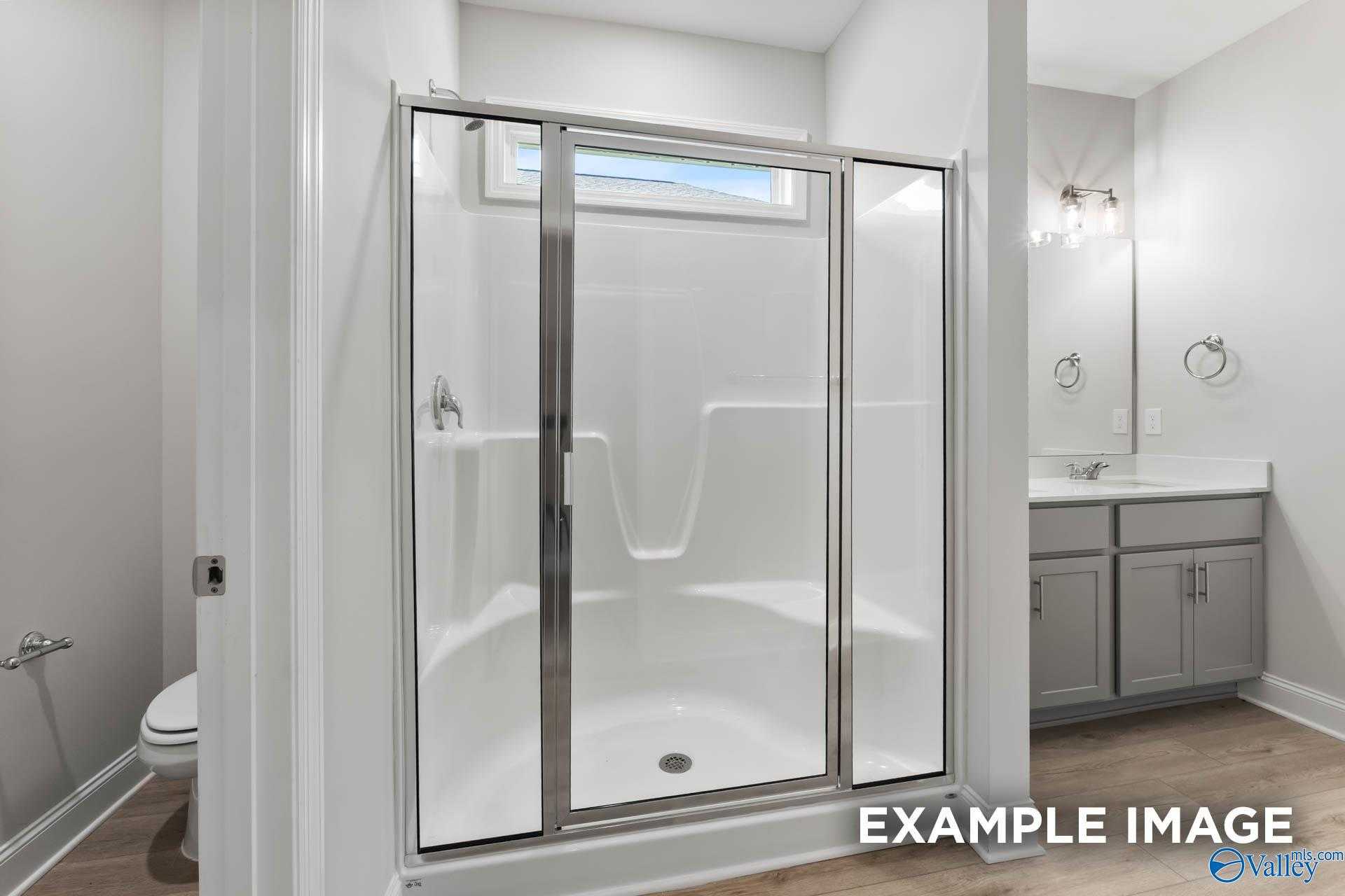 Modern bathroom with frameless glass shower, subway tile walls, and gray shaker vanity in Davidson Homes The Daphne C, New Market, Alabama