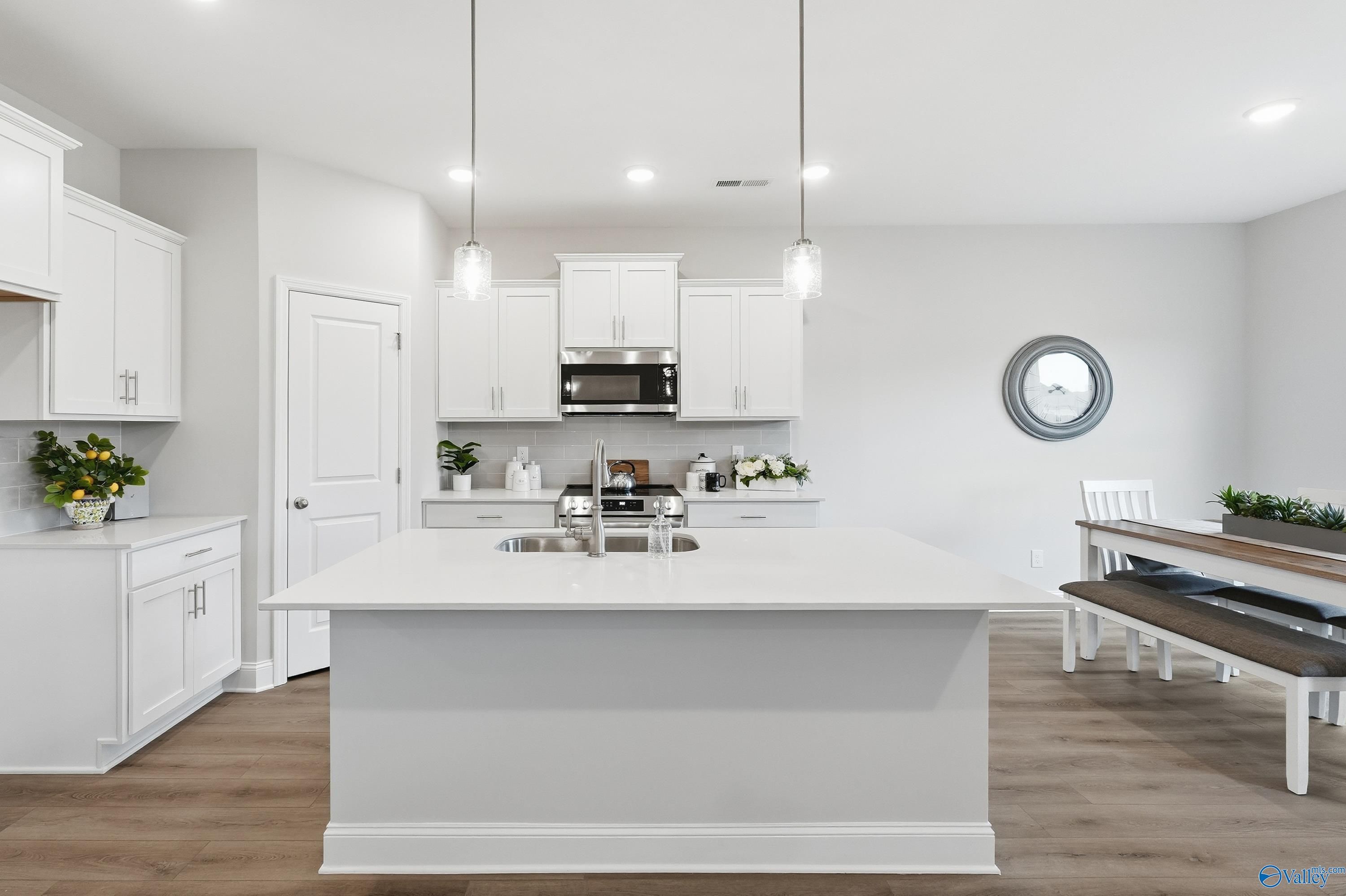 Modern white shaker kitchen island with stainless appliances and open dining area in Davidson Homes The Asheville, Toney, Alabama