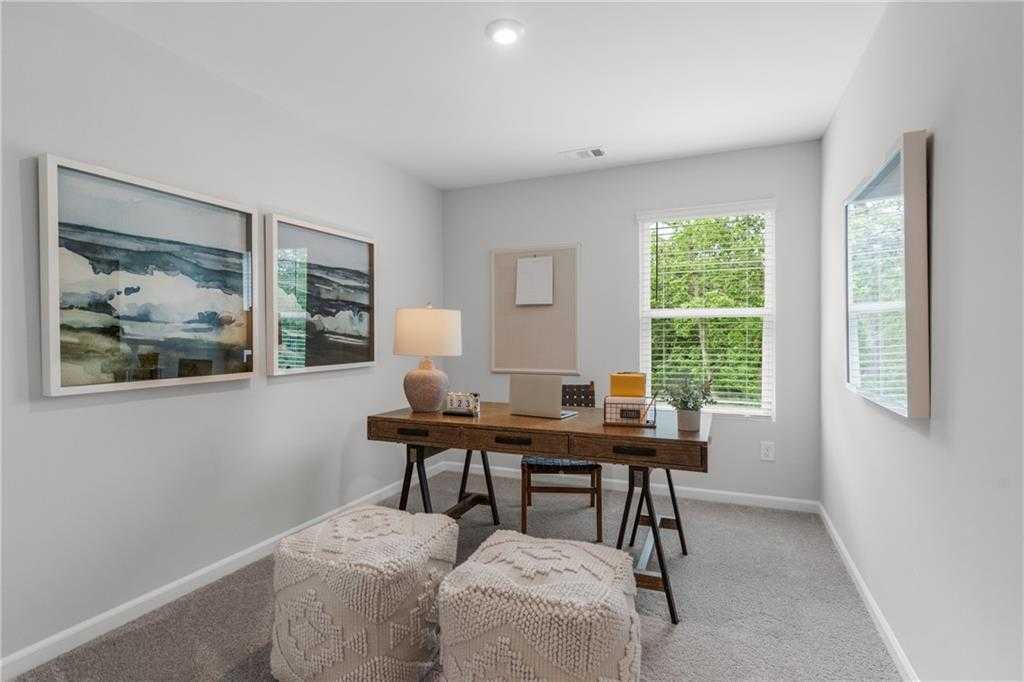 Cozy home office with wooden sawhorse desk, laptop, ocean artwork, and window view in Davidson Homes The Durant A, Emerson, Georgia