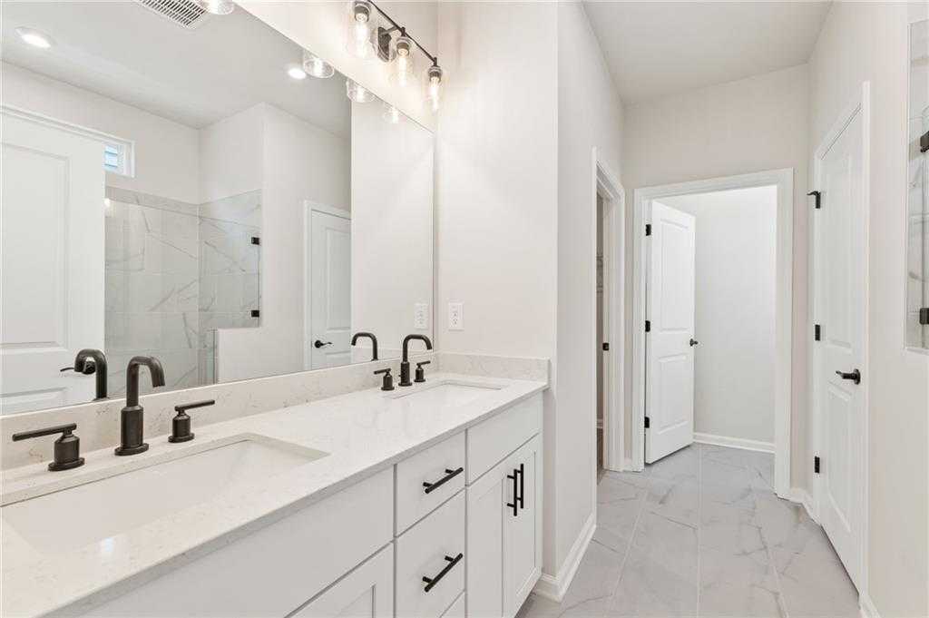 Modern master bathroom featuring double white vanity, black faucets, subway tile shower in Davidson Homes The Daphne C, Loganville, GA