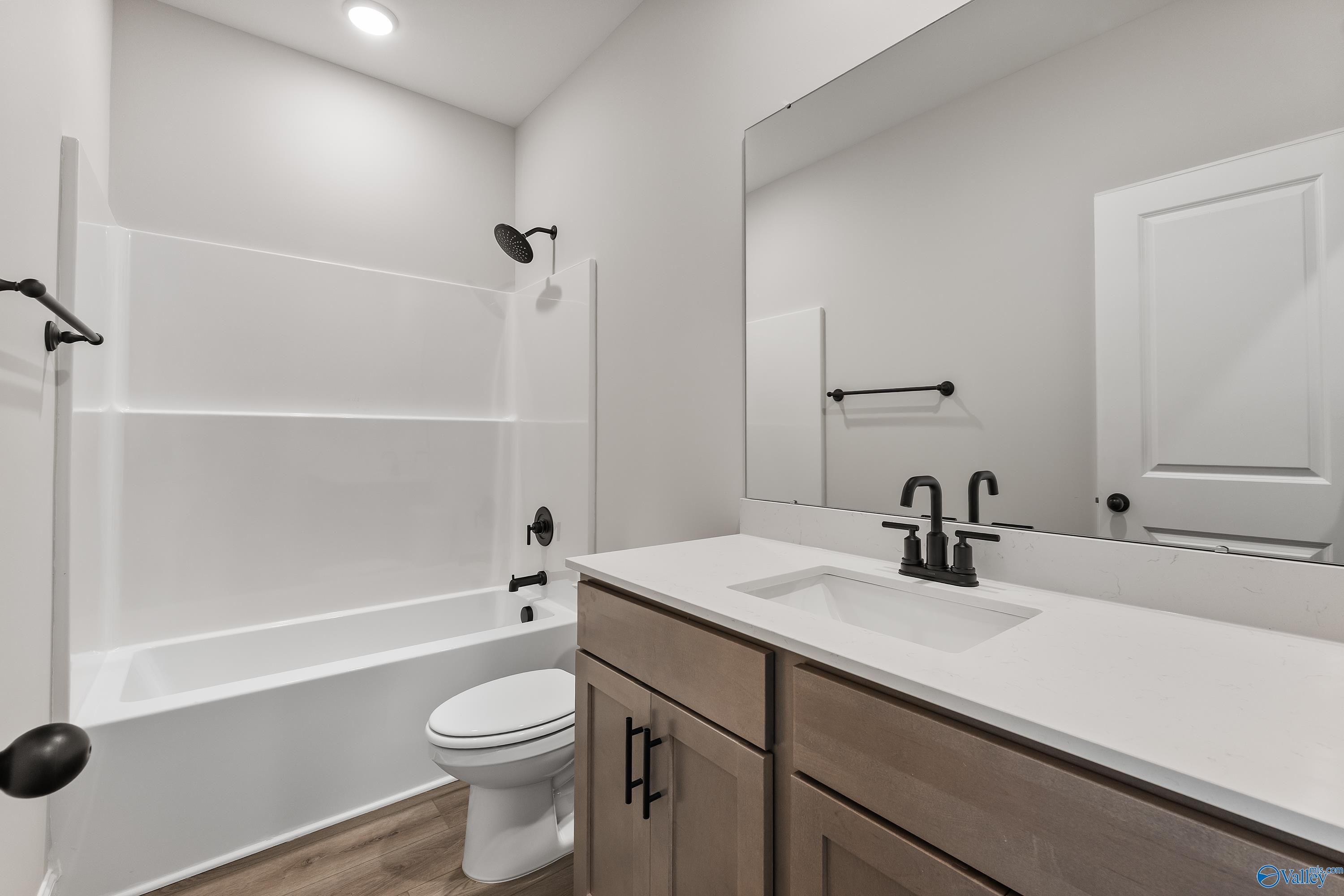 Bright bathroom with white tub-shower combo, shaker vanity, black fixtures in Davidson Homes The Daphne, Huntsville AL