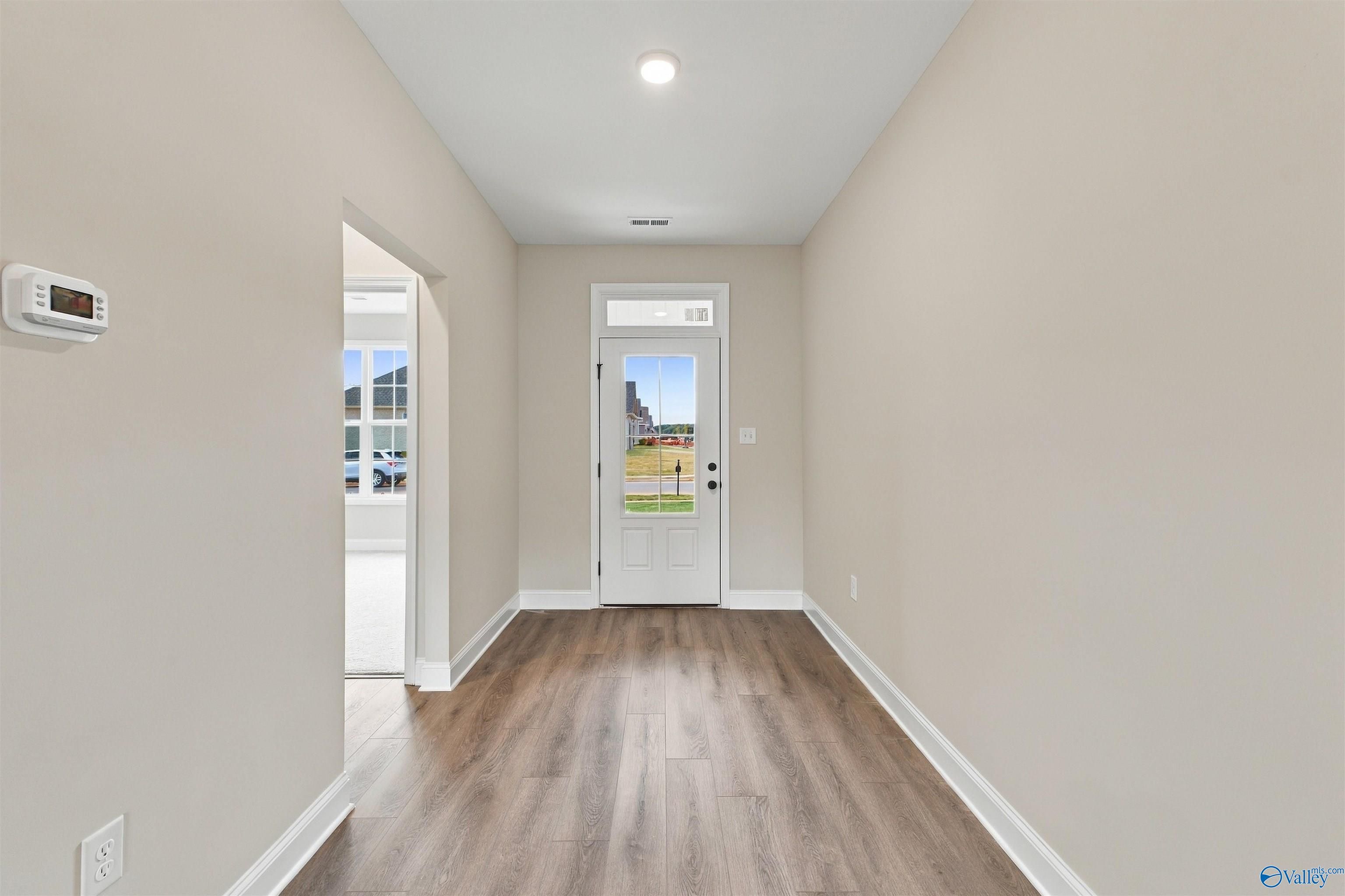 Bright foyer with wood-look flooring and white glass-panel front door in Davidson Homes' The Montgomery, Decatur, Alabama