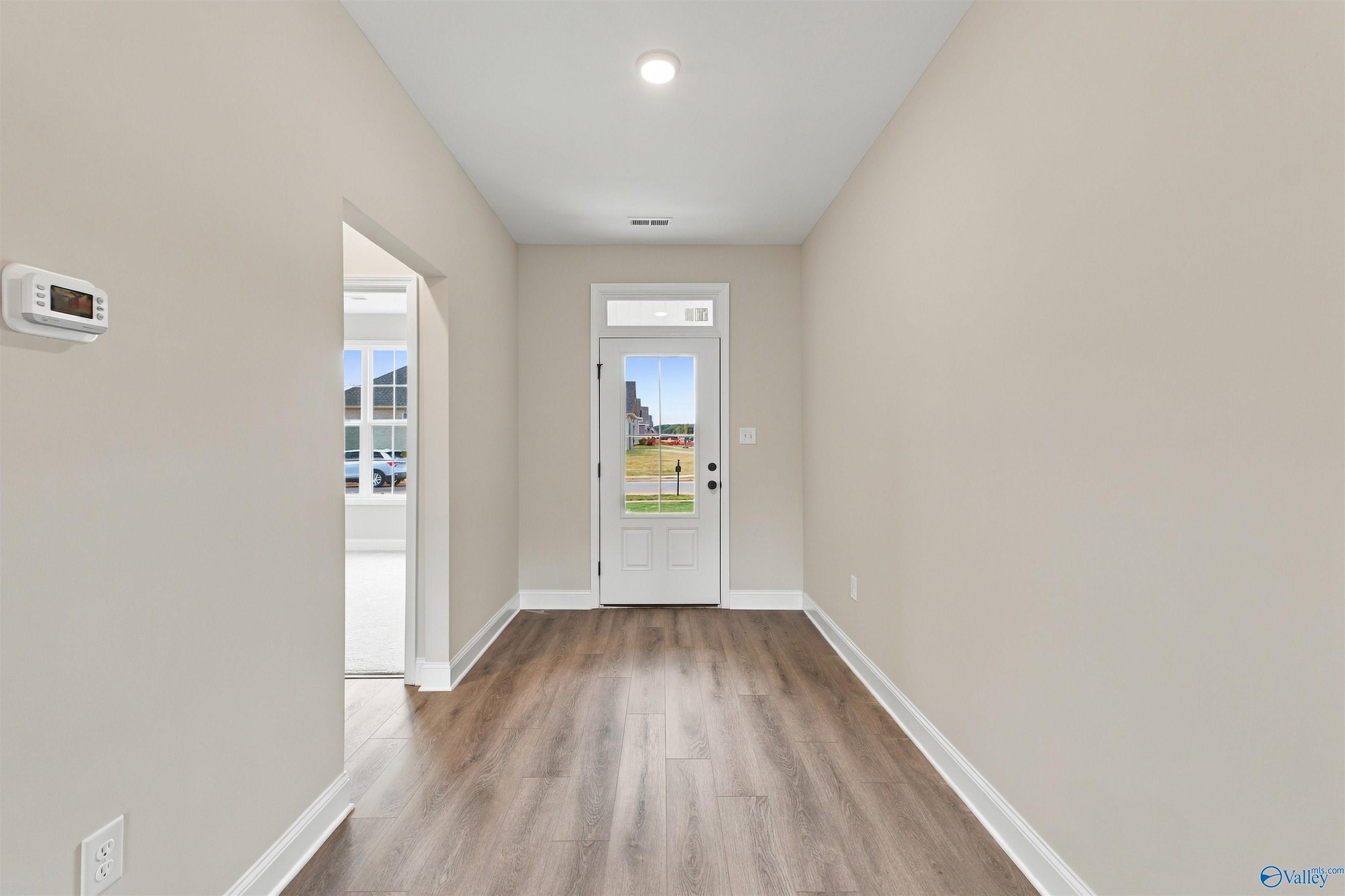 Bright foyer with wood-look flooring and white glass-panel front door in Davidson Homes' The Montgomery, Decatur, Alabama