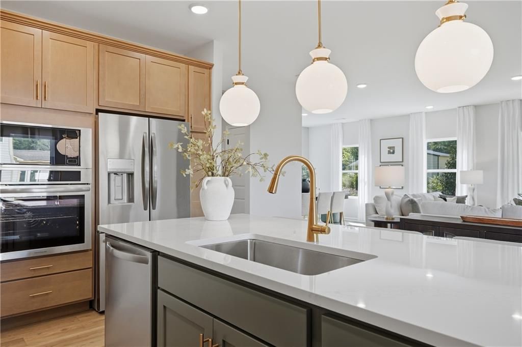 Kitchen island with white quartz countertop, gold faucet, and pendant lights in Davidson Homes Sinclair B, Cartersville, Georgia