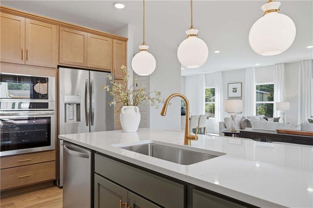 Kitchen island with white quartz countertop, gold faucet, and pendant lights in Davidson Homes Sinclair B, Cartersville, Georgia