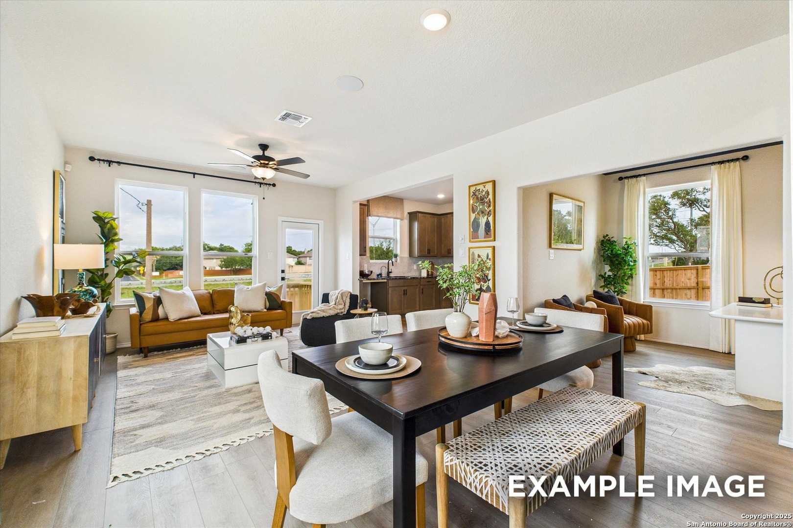 Bright open-concept living and dining room with leather sofa, wooden table, large windows in Davidson Homes The Florence C, San Antonio