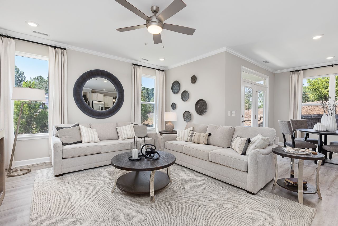Modern living room at Woodland Crossing in Zebulon, NC, featuring neutral furniture, a round coffee table, and decor.