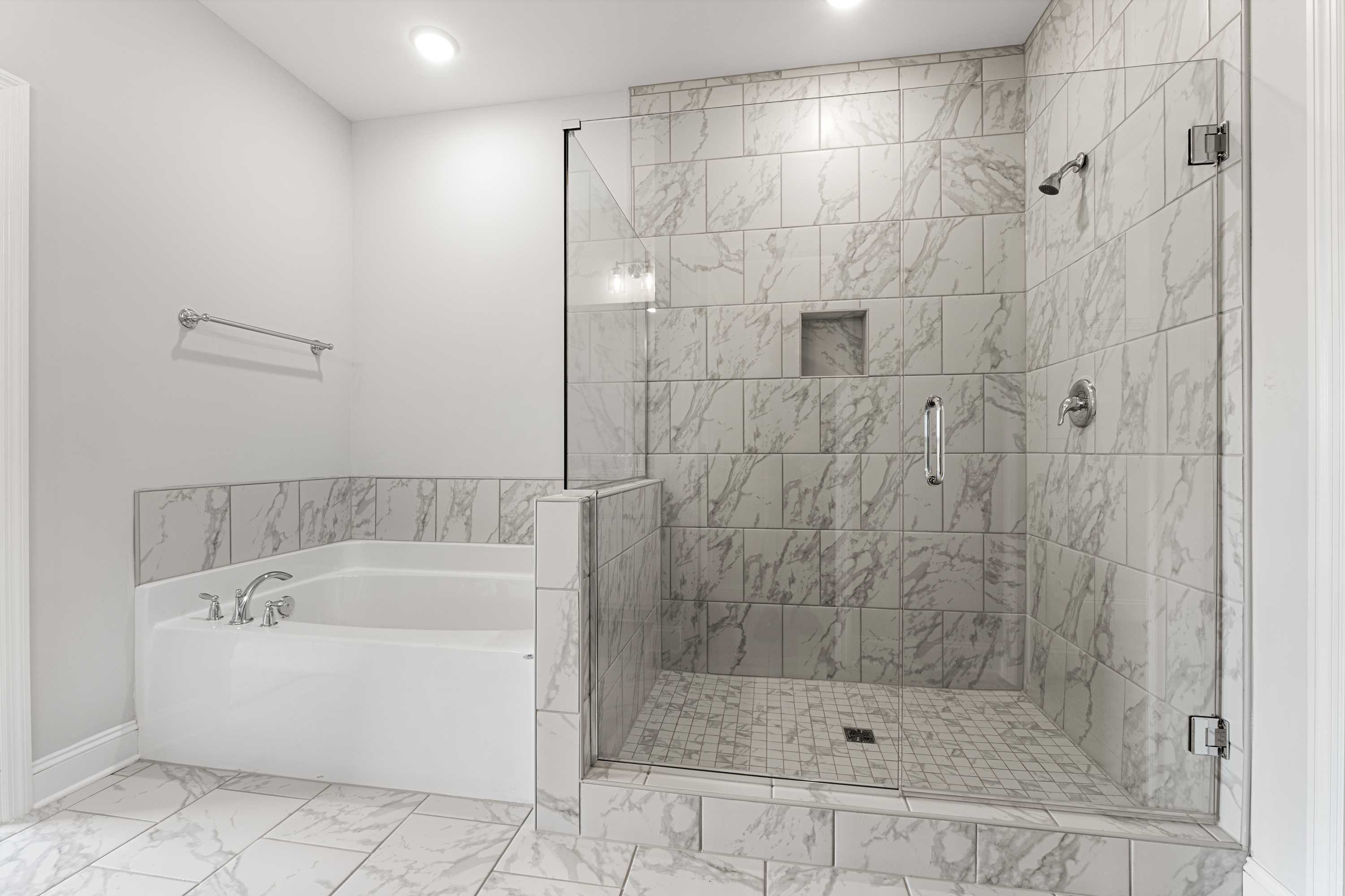 Luxurious master bathroom in The Copeland B with glass-enclosed tiled shower and freestanding soaking tub