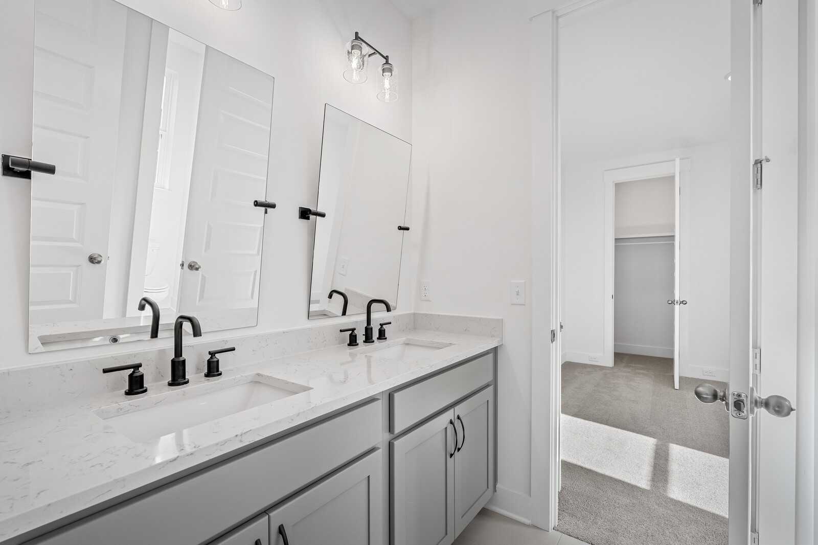 Modern double-sink vanity with quartz countertop, gray cabinets, and mirrors in The Alston A bathroom by Davidson Homes, Murfreesboro, TN
