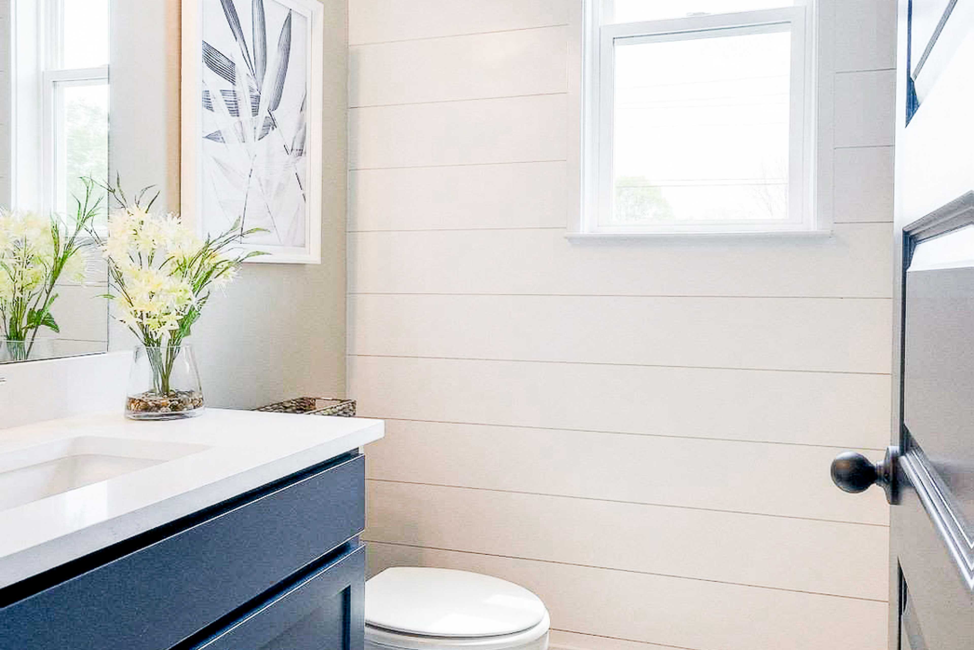 Cozy bathroom at The Meadows in Smyrna TN featuring white shiplap walls, navy vanity, plaid window valance, and natural light