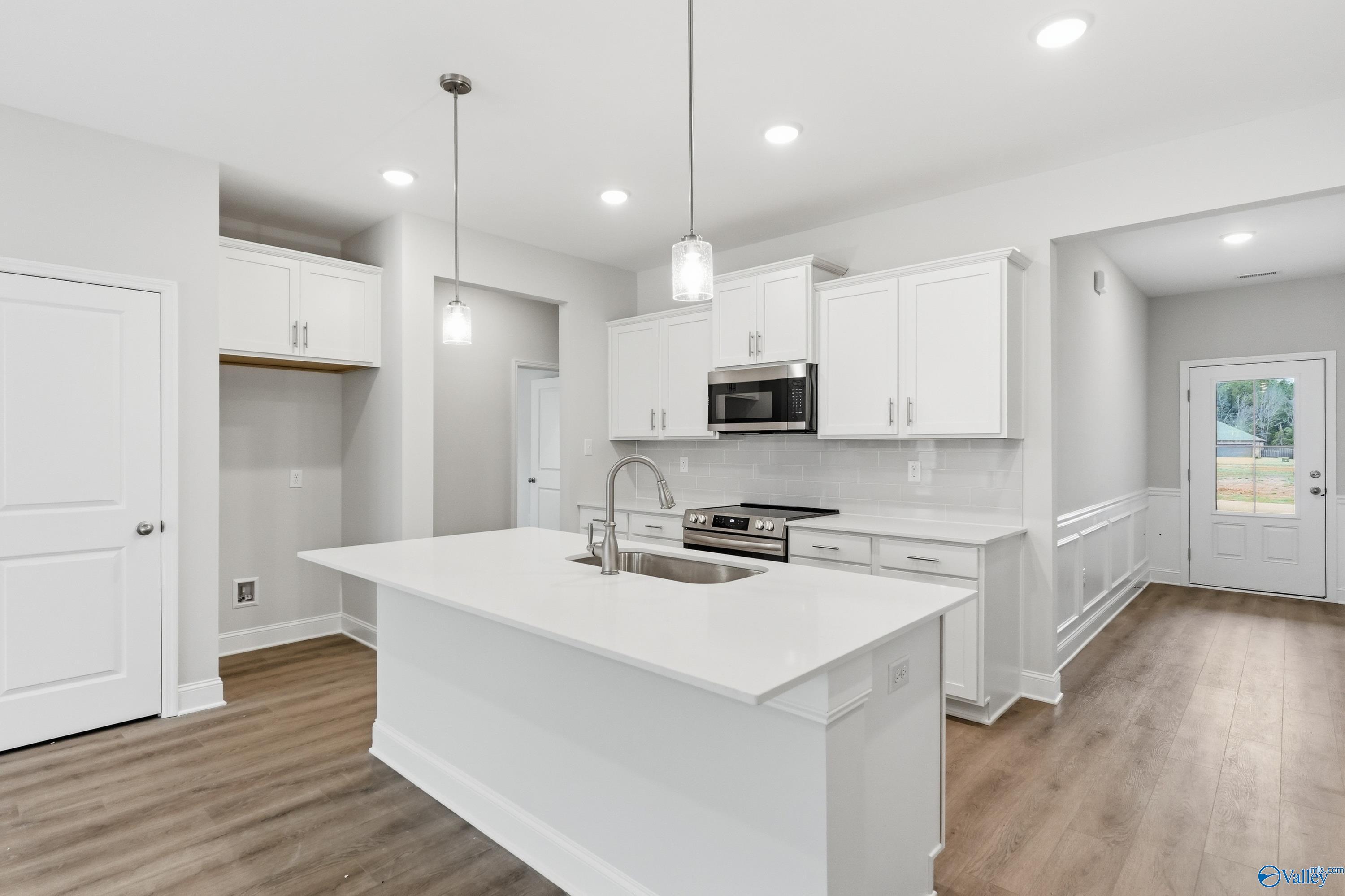 Modern white kitchen island with sink, stainless steel appliances, and open layout in Davidson Homes The Cumberland, Decatur AL