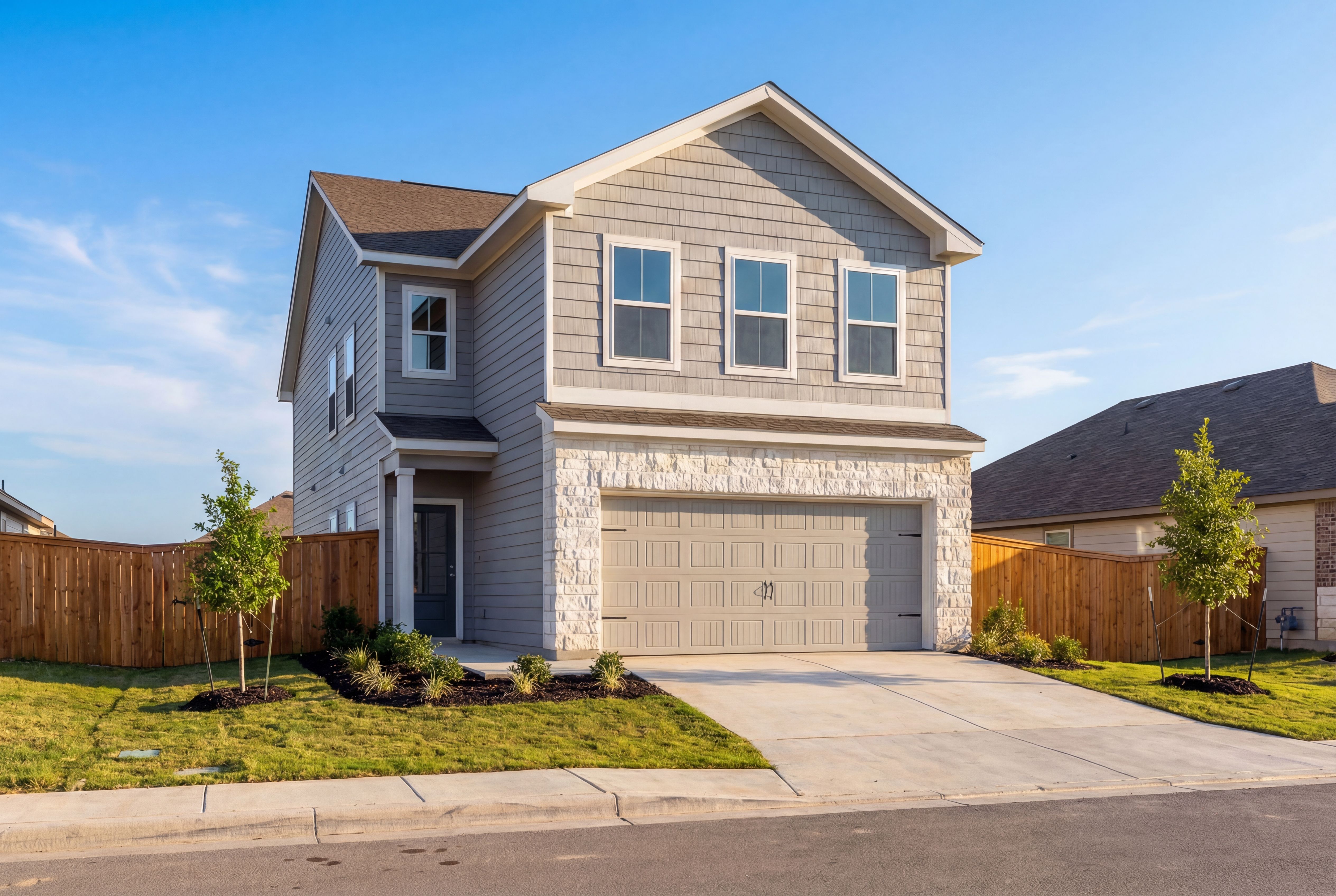 Two-story Gillian B home elevation by Davidson Homes featuring gray siding, stone accents, two-car garage, and landscaped front yard