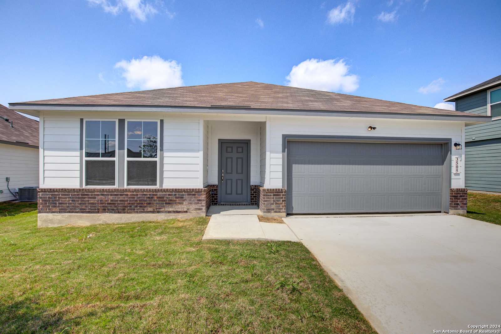 Modern single-story 4-bedroom home with 2-car garage, white brick exterior, and green lawn in Hannah Heights, Seguin, Texas