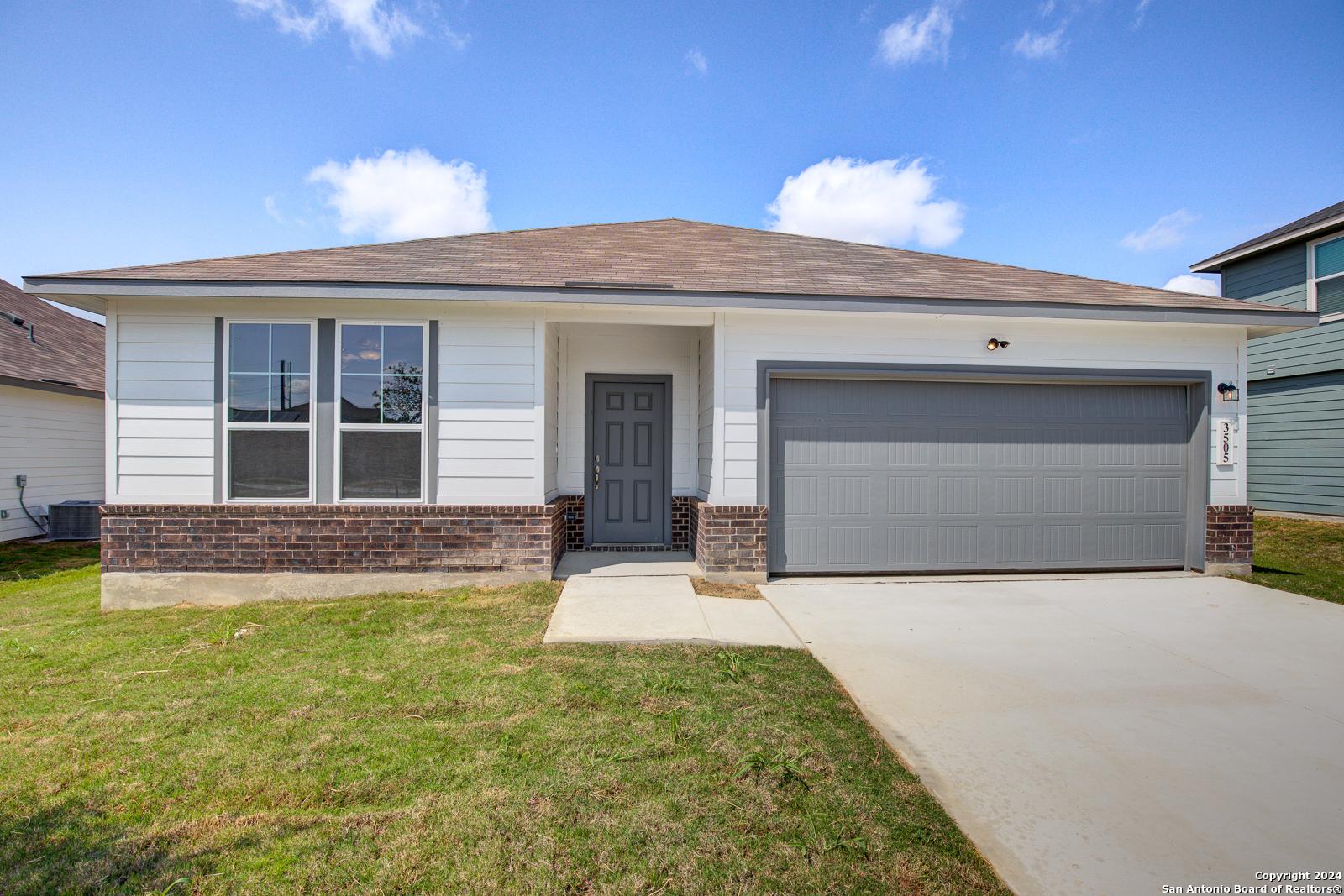 Modern single-story 4-bedroom home with 2-car garage, white brick exterior, and green lawn in Hannah Heights, Seguin, Texas
