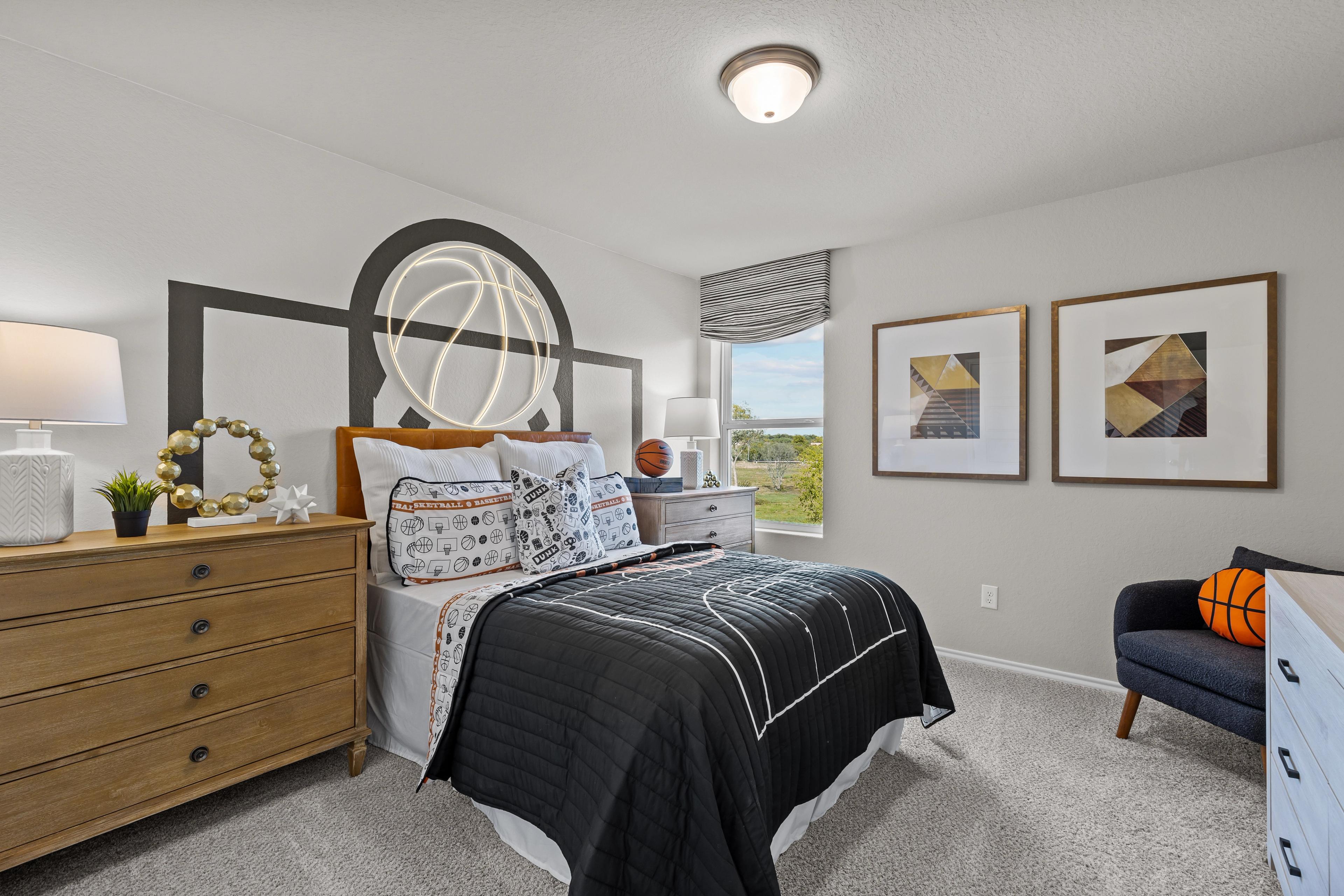 Basketball-themed bedroom in The Sabine B showcasing hoop headboard, black quilted bedding, dresser, and abstract art in San Antonio home
