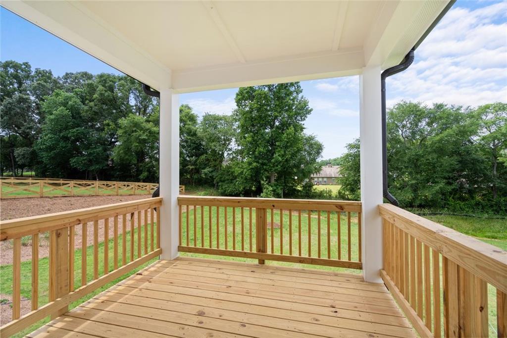 Covered wooden deck with white columns and railings overlooking lush backyard in Wehunt Meadows, Hoschton, Georgia