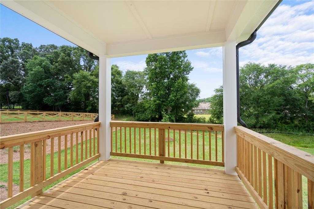 Covered wooden deck with white columns and railings overlooking lush backyard in Wehunt Meadows, Hoschton, Georgia