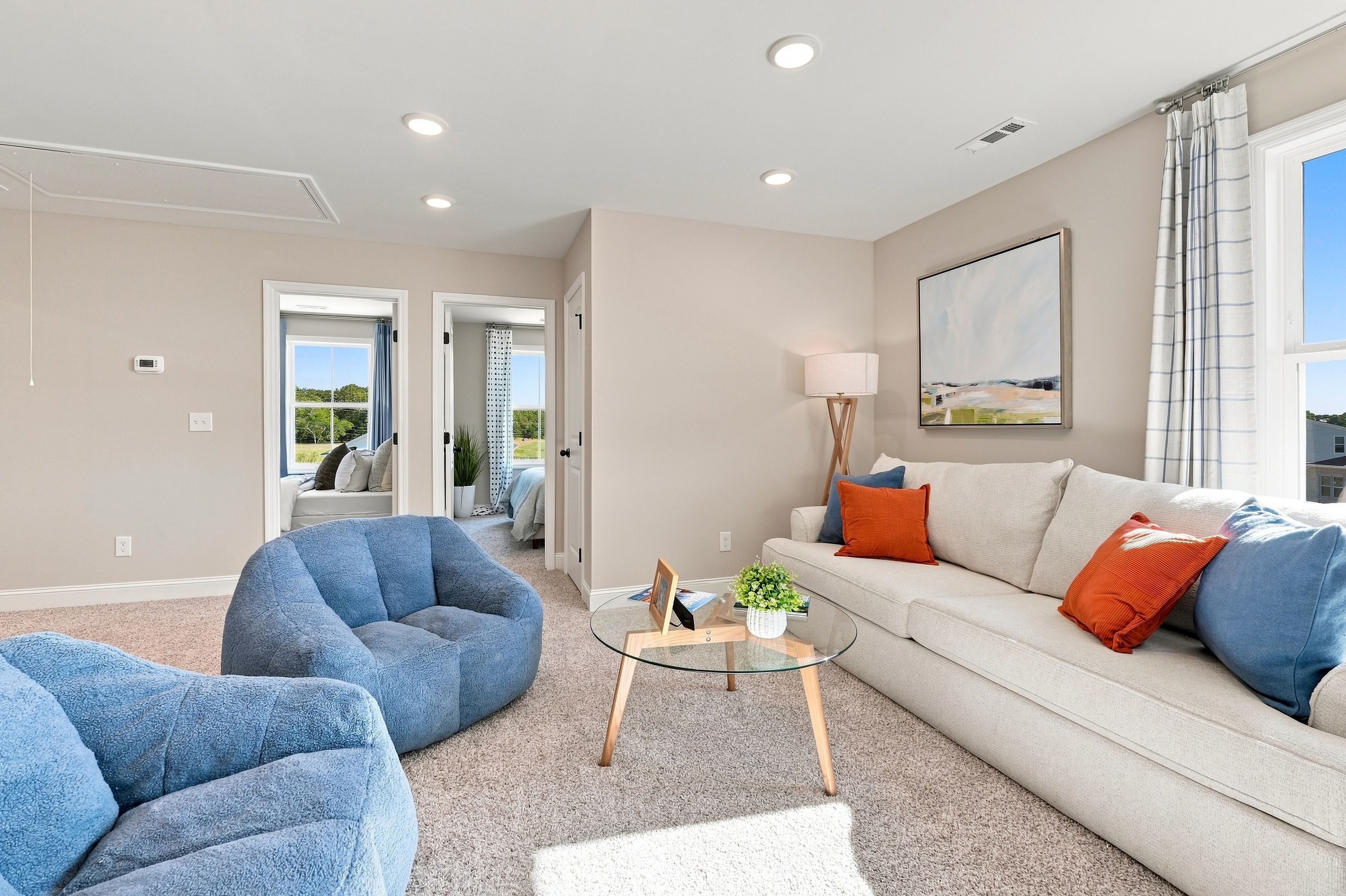 Bright bonus living room at Bailey Park in Fayetteville, TN by Davidson Homes with white sofa, blue chairs, glass coffee table