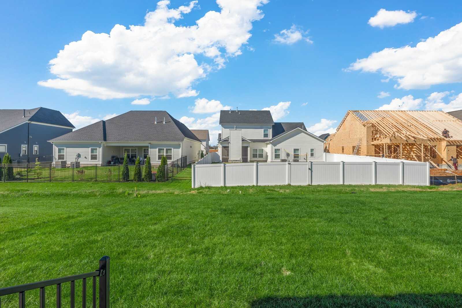 New construction two-story homes with garages, white vinyl fences, and green lawns in Shelton Square, Murfreesboro, Tennessee by Davidson Homes
