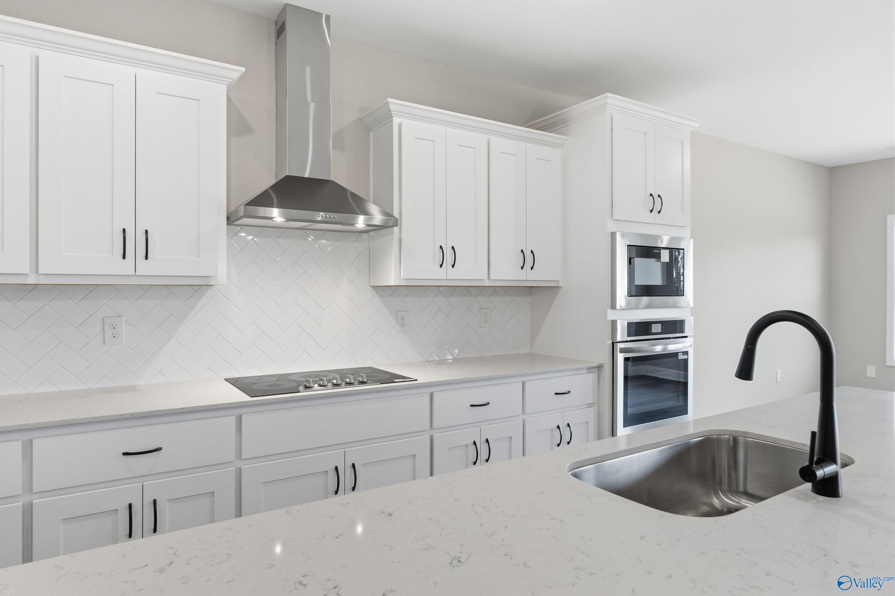 Modern white shaker kitchen with stainless steel double oven, gas cooktop, subway tile backsplash in Davidson Homes The Finleigh, Meridianville, AL