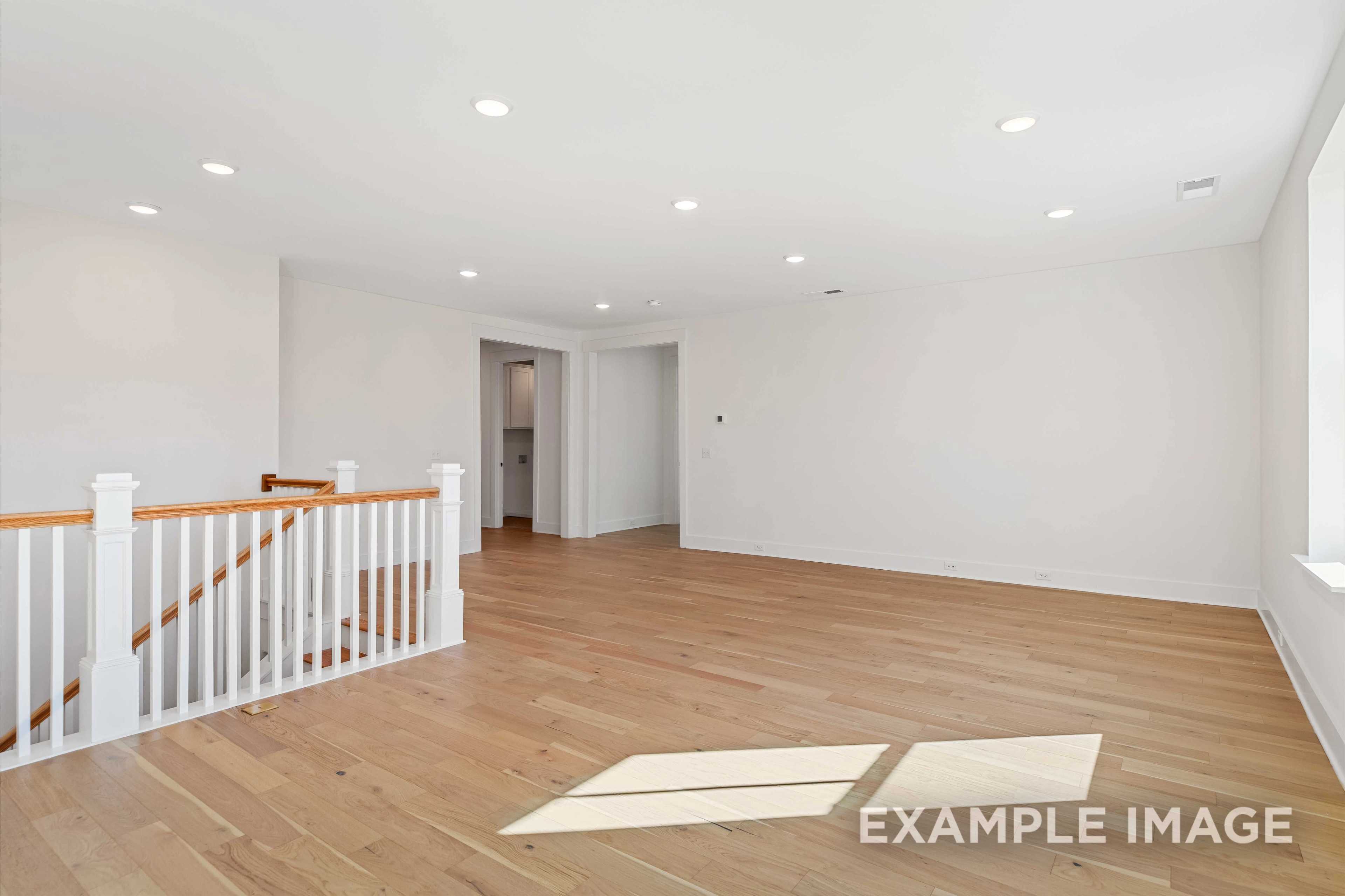 Spacious upper floor loft in The Albany A with hardwood floors, white walls, oak staircase, and recessed lighting