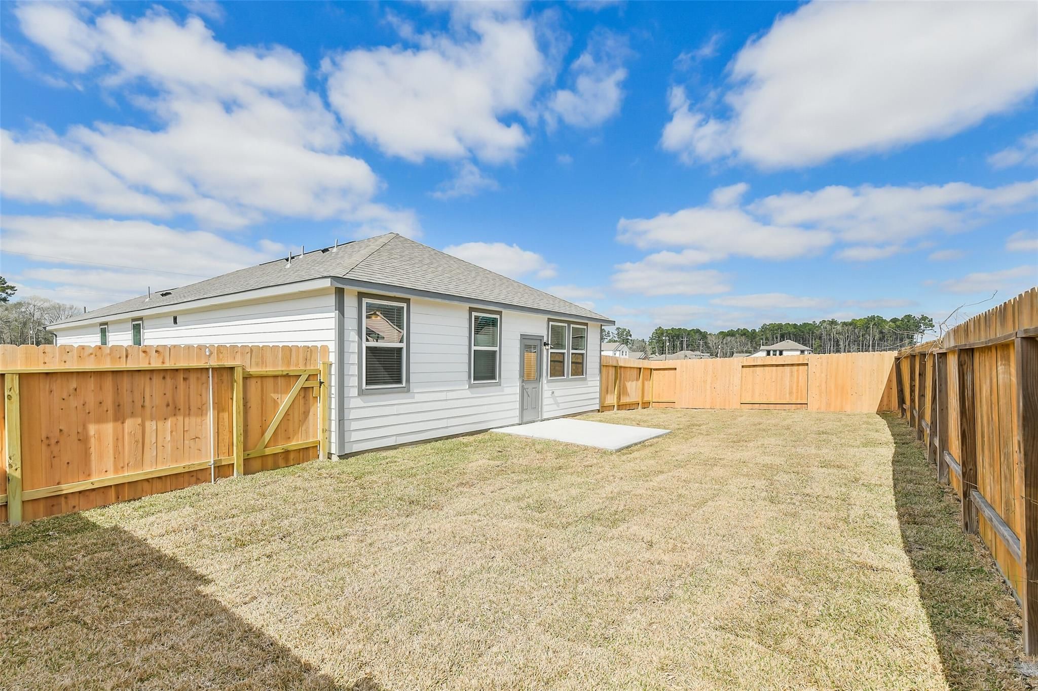 Backyard of single-story 4-bedroom Davidson Homes The Colorado F in Liberty Estates, Cleveland, Texas, with wooden fence and grassy yard