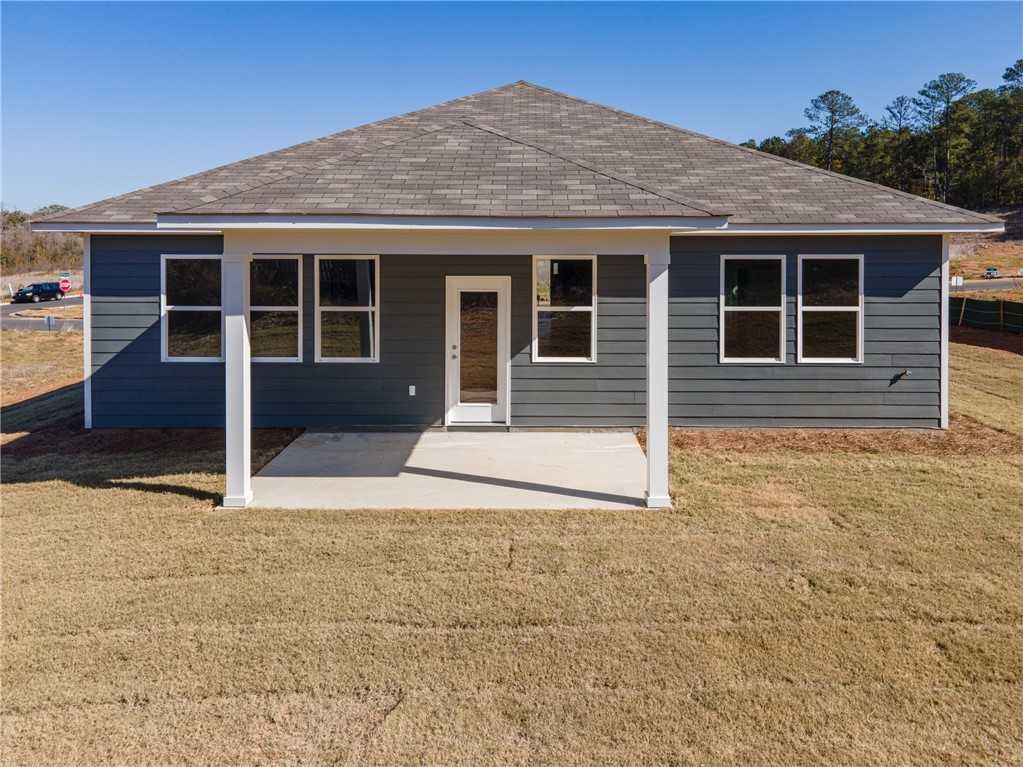Rear view of The Luna B single-story home featuring covered patio, gray siding, and grassy yard in Anderson Lakes, Opelika, Alabama