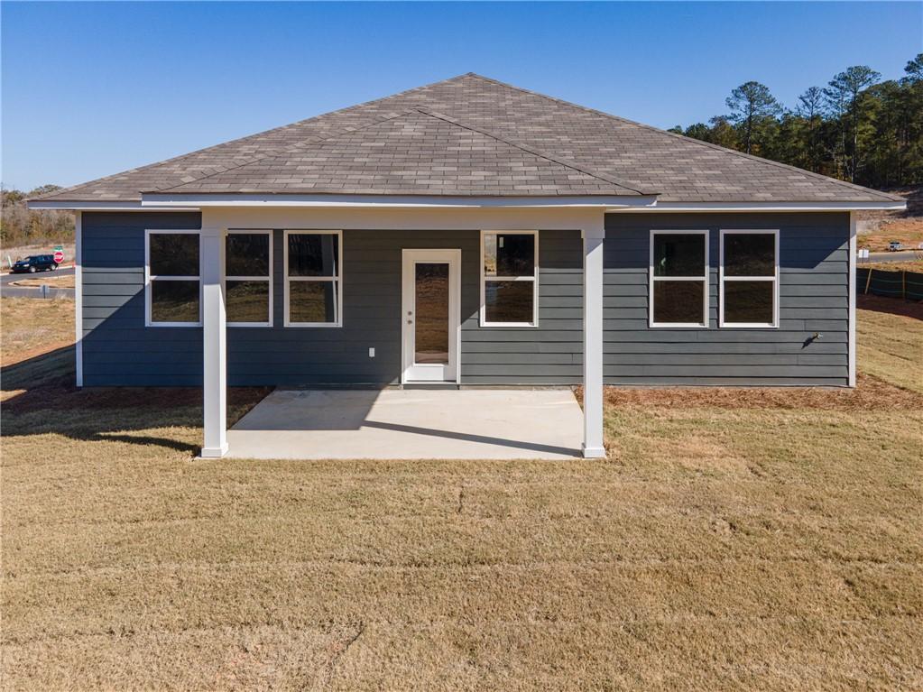 Rear view of The Luna B single-story home featuring covered patio, gray siding, and grassy yard in Anderson Lakes, Opelika, Alabama