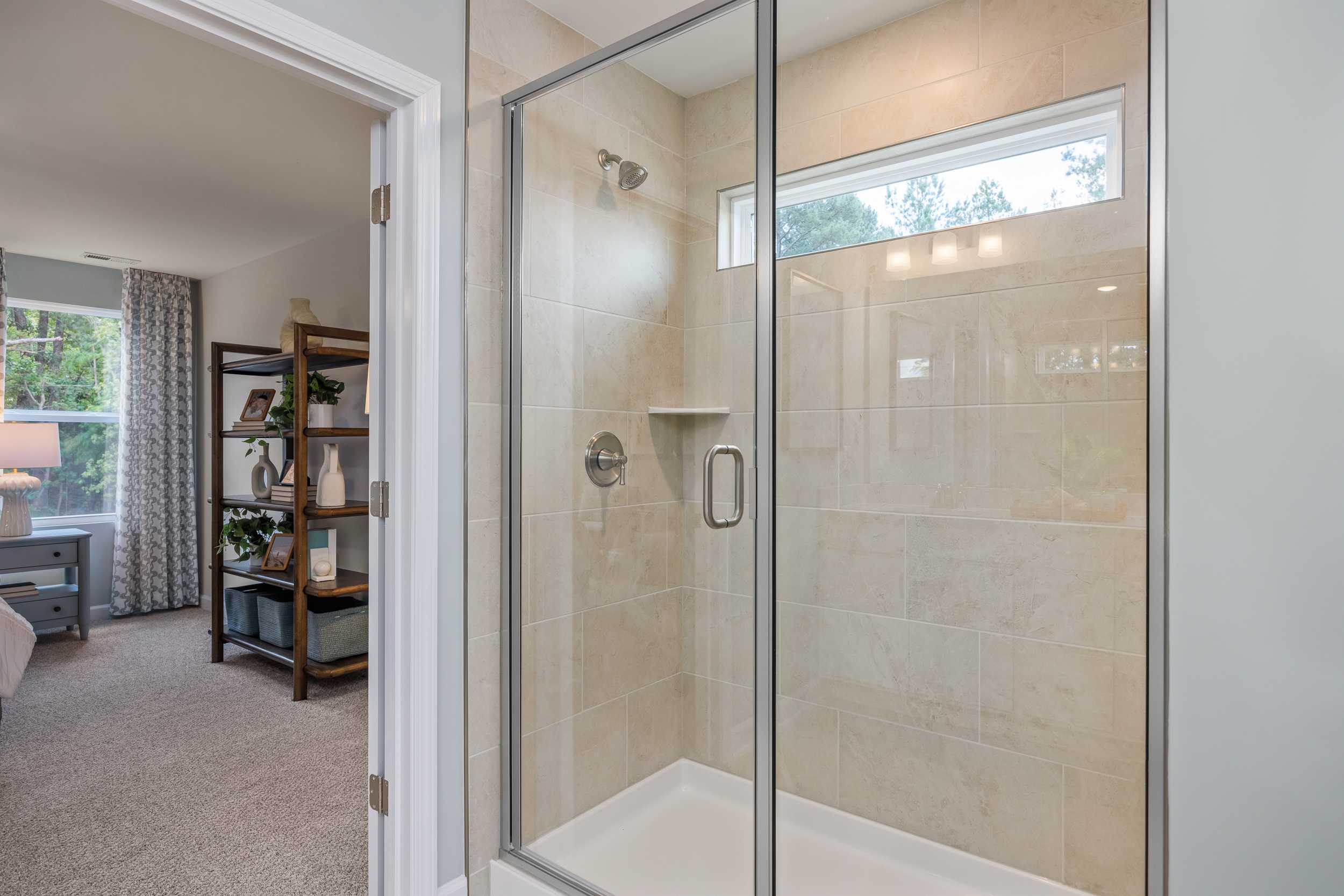 Frameless glass walk-in shower in master bathroom at The Retreat at North Main in Lillington NC with subway tile and clerestory window