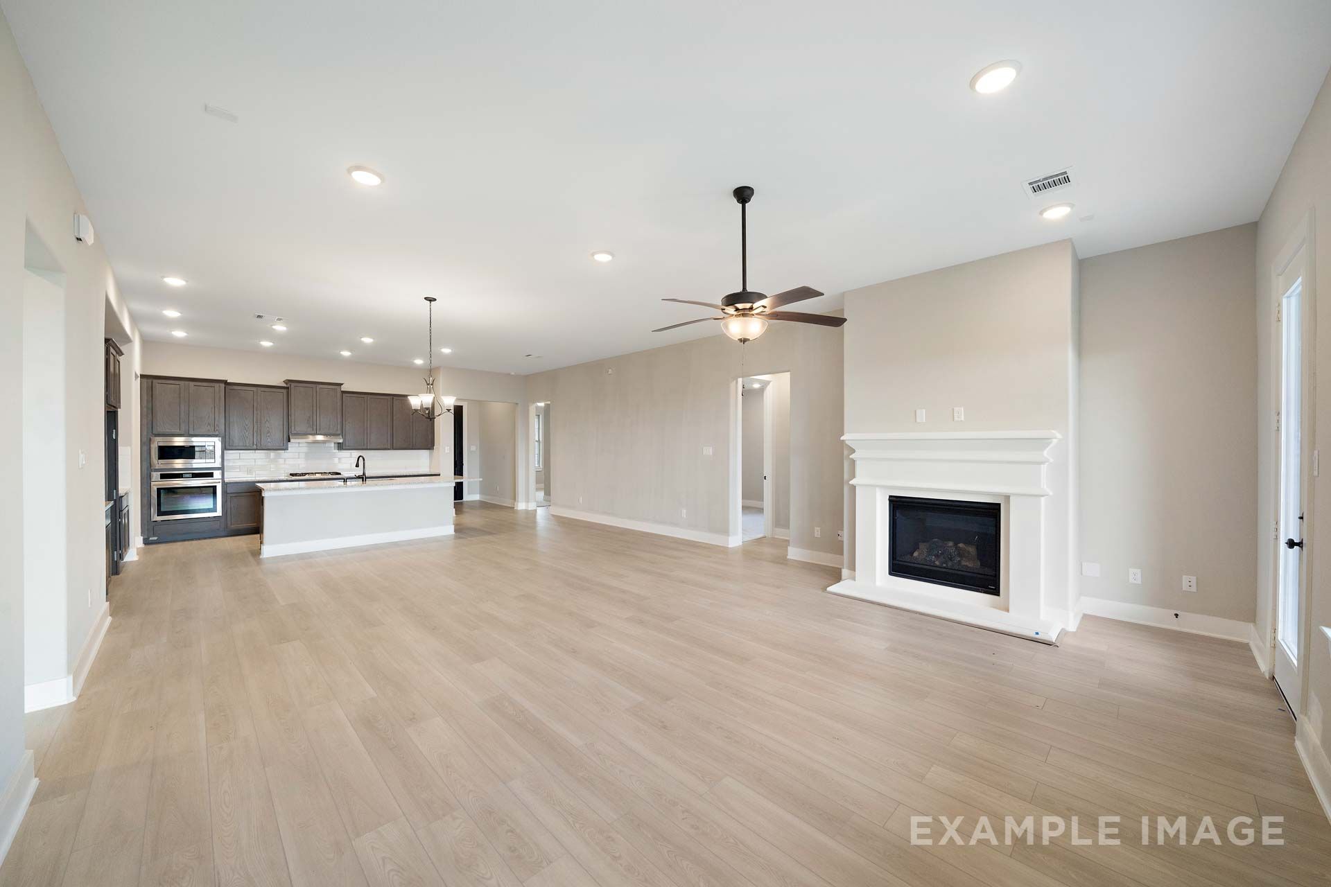 Open-concept living and kitchen in The Elizabeth by Davidson Homes, featuring fireplace, island, and hardwood-style flooring.