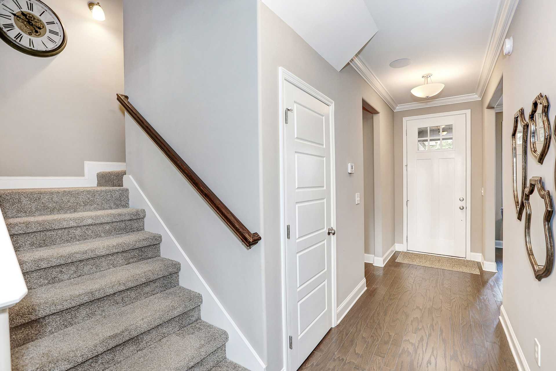Elegant entryway staircase at Stone Creek Phase II in Cullman AL with gray carpet steps, hardwood floors, white doors and chandelier