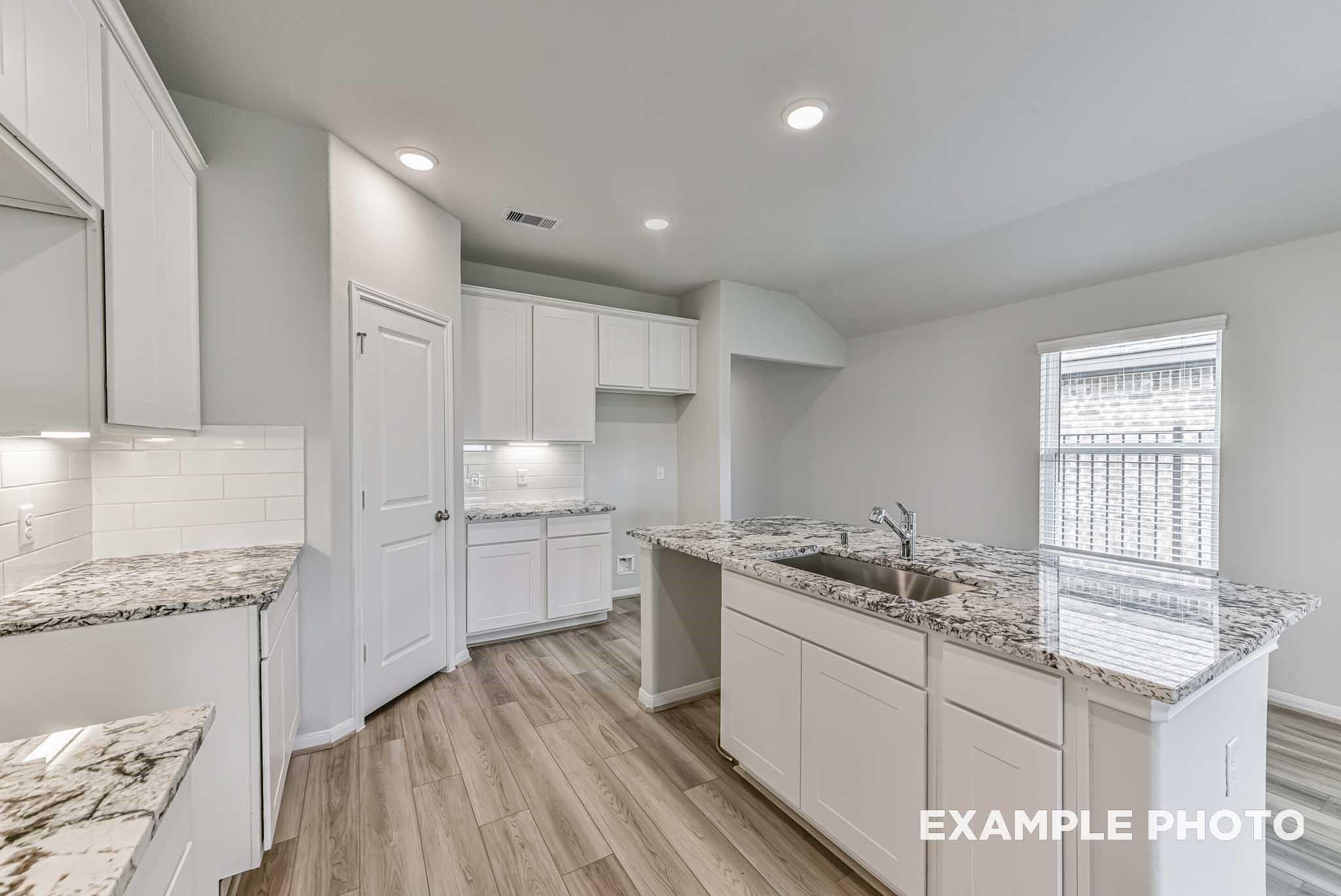 Bright modern kitchen with white cabinets, granite island sink, subway tile backsplash in Davidson Homes The Riviera A, Rosharon, Texas