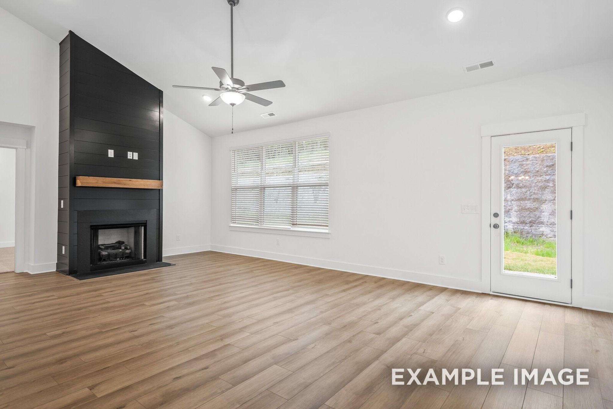 Spacious living room with black stone fireplace, ceiling fan, large windows, and French doors to backyard in Davidson Homes Ridgeport C, Gallatin, TN