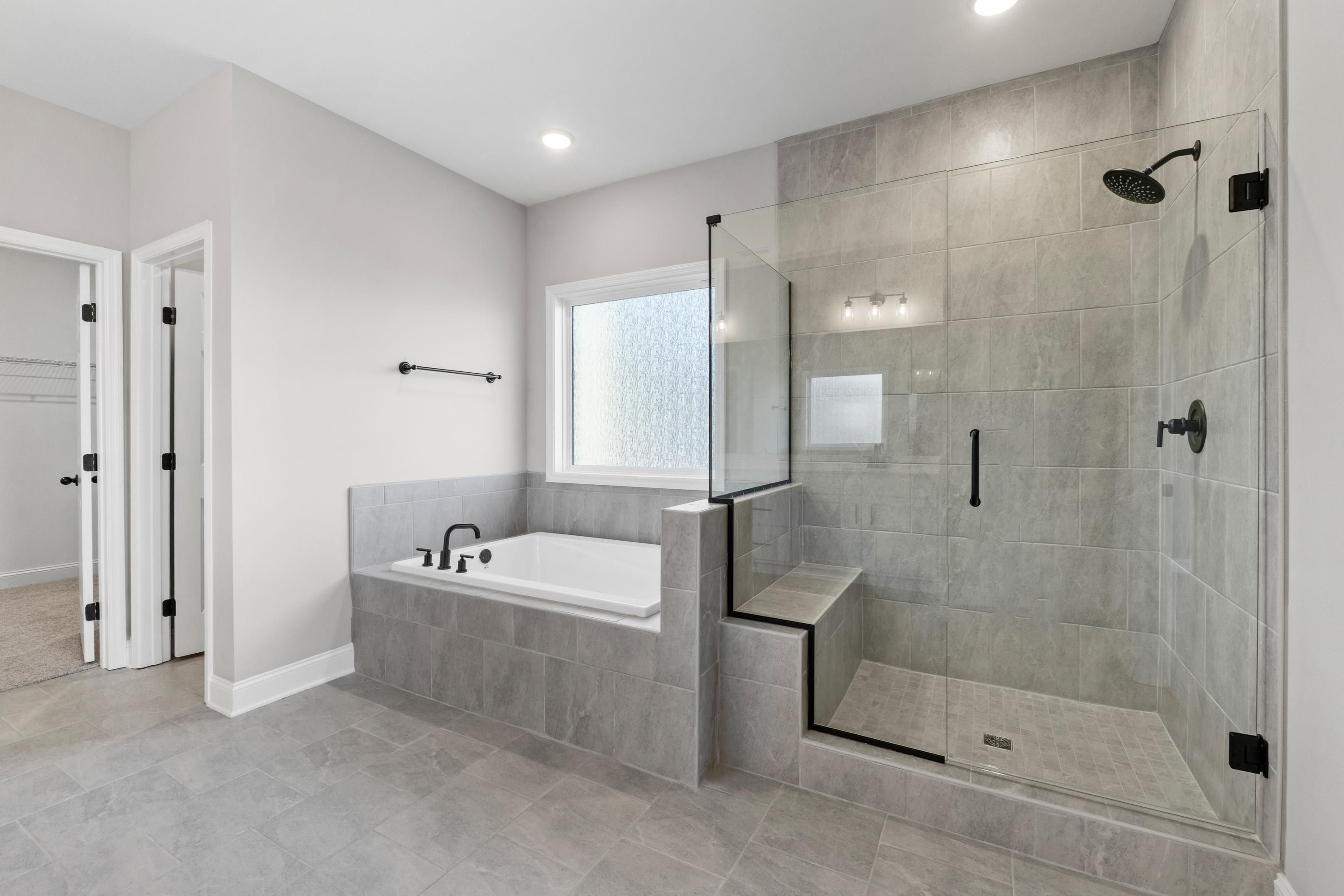 Luxury master bathroom in The Valencia by Davidson Homes featuring freestanding tub, glass shower, and gray tile design