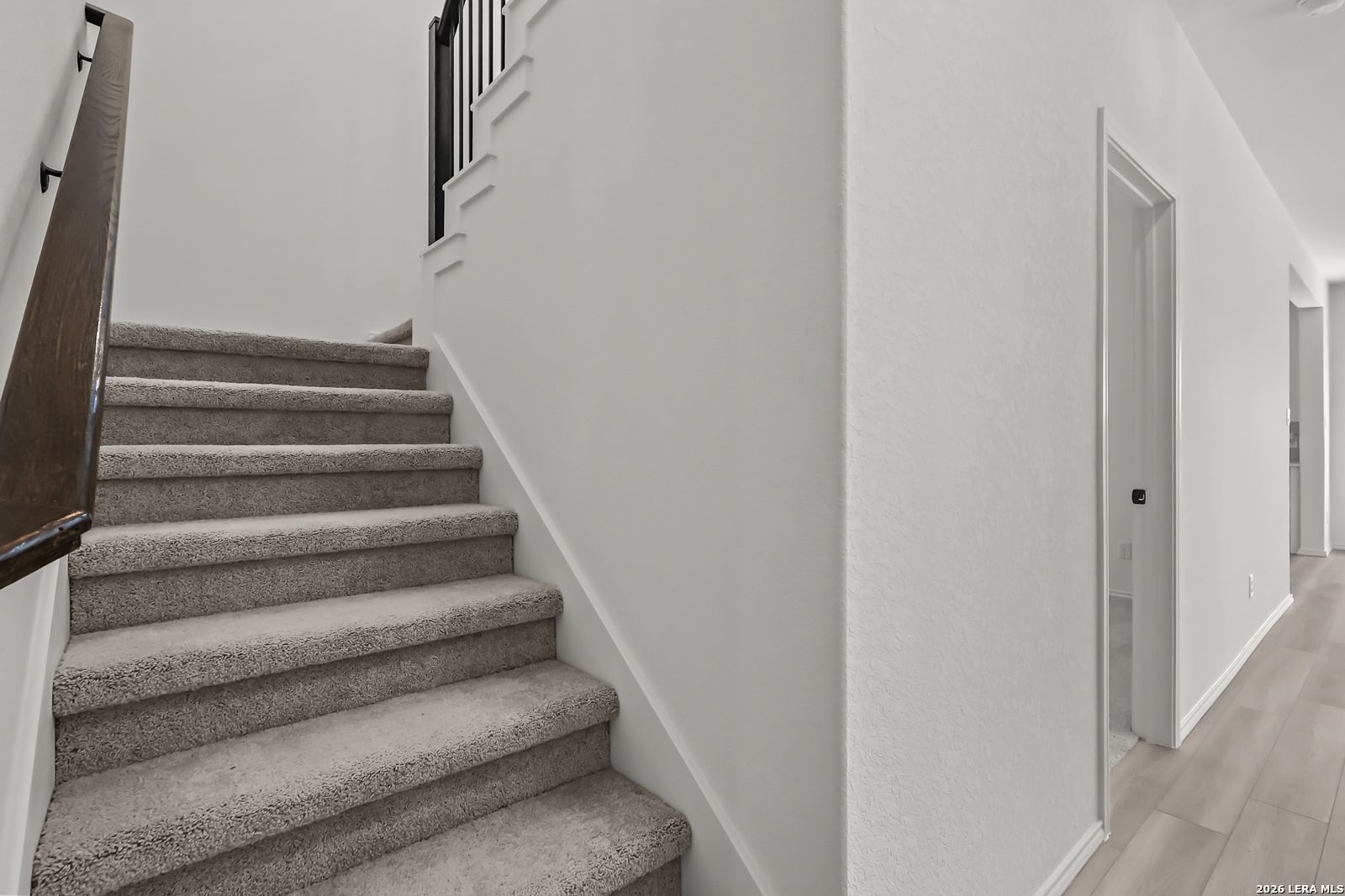 Carpeted staircase with wooden handrail in The Florence B floor plan at Meadows at Oak Creek, San Antonio, Texas.