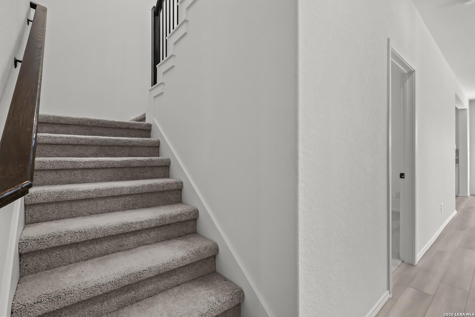 Carpeted staircase with wooden handrail in The Florence B floor plan at Meadows at Oak Creek, San Antonio, Texas.