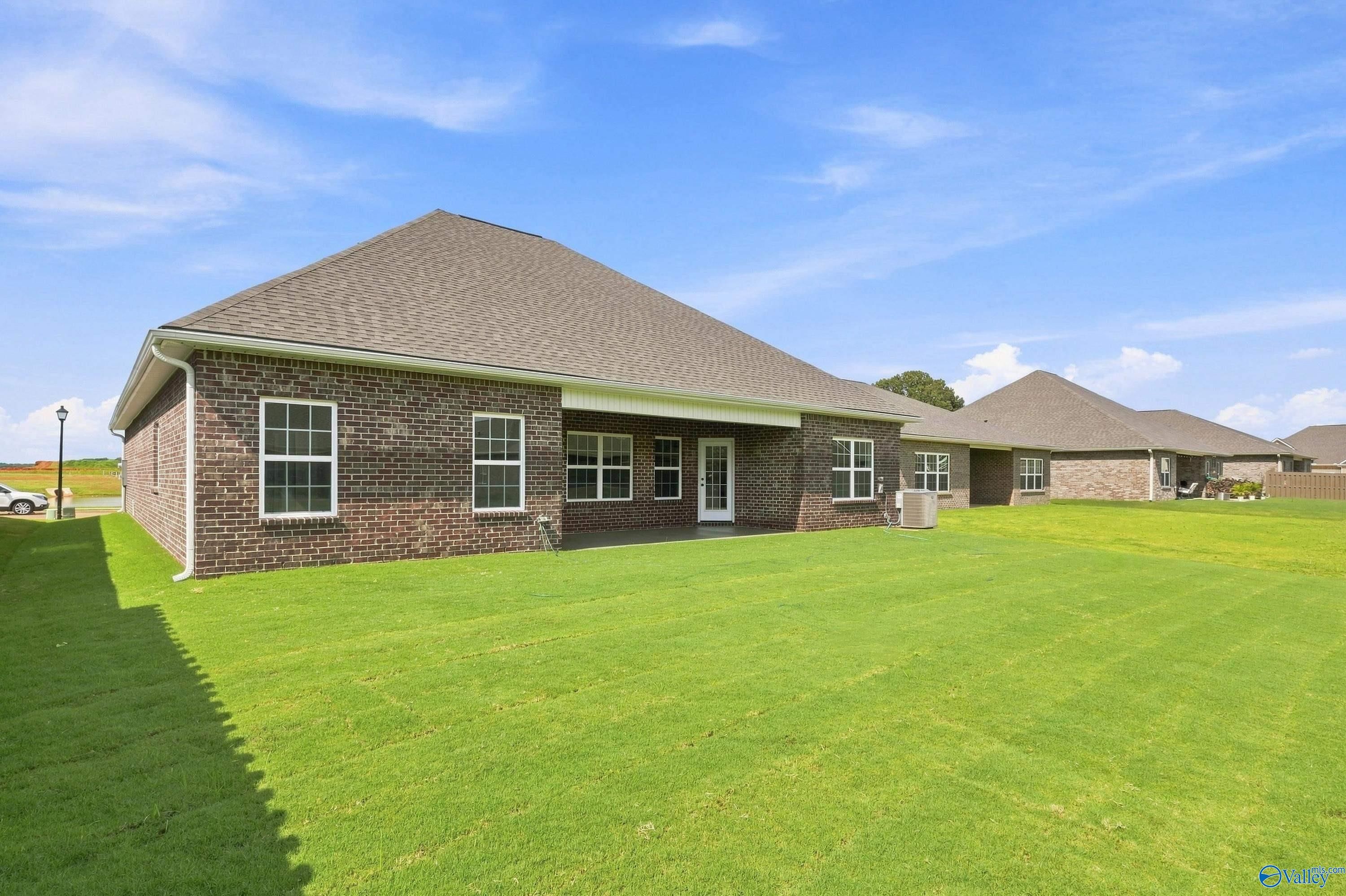 Brick exterior of The Rockford B floor plan with a spacious backyard in Kendall Downs, Toney, Alabama.