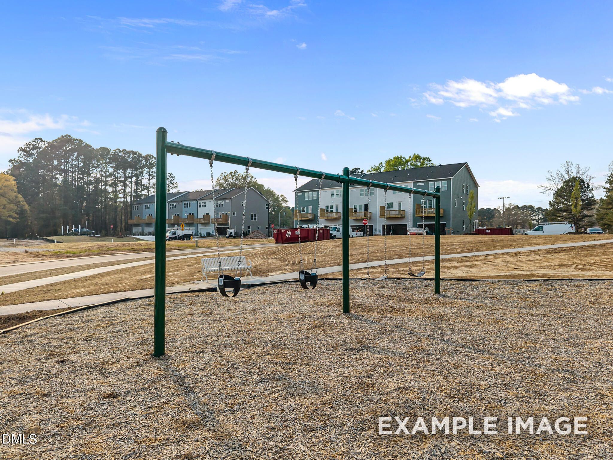 Playground swings on green metal frame in mulch area at Camden Park, Knightdale, North Carolina, near new townhomes