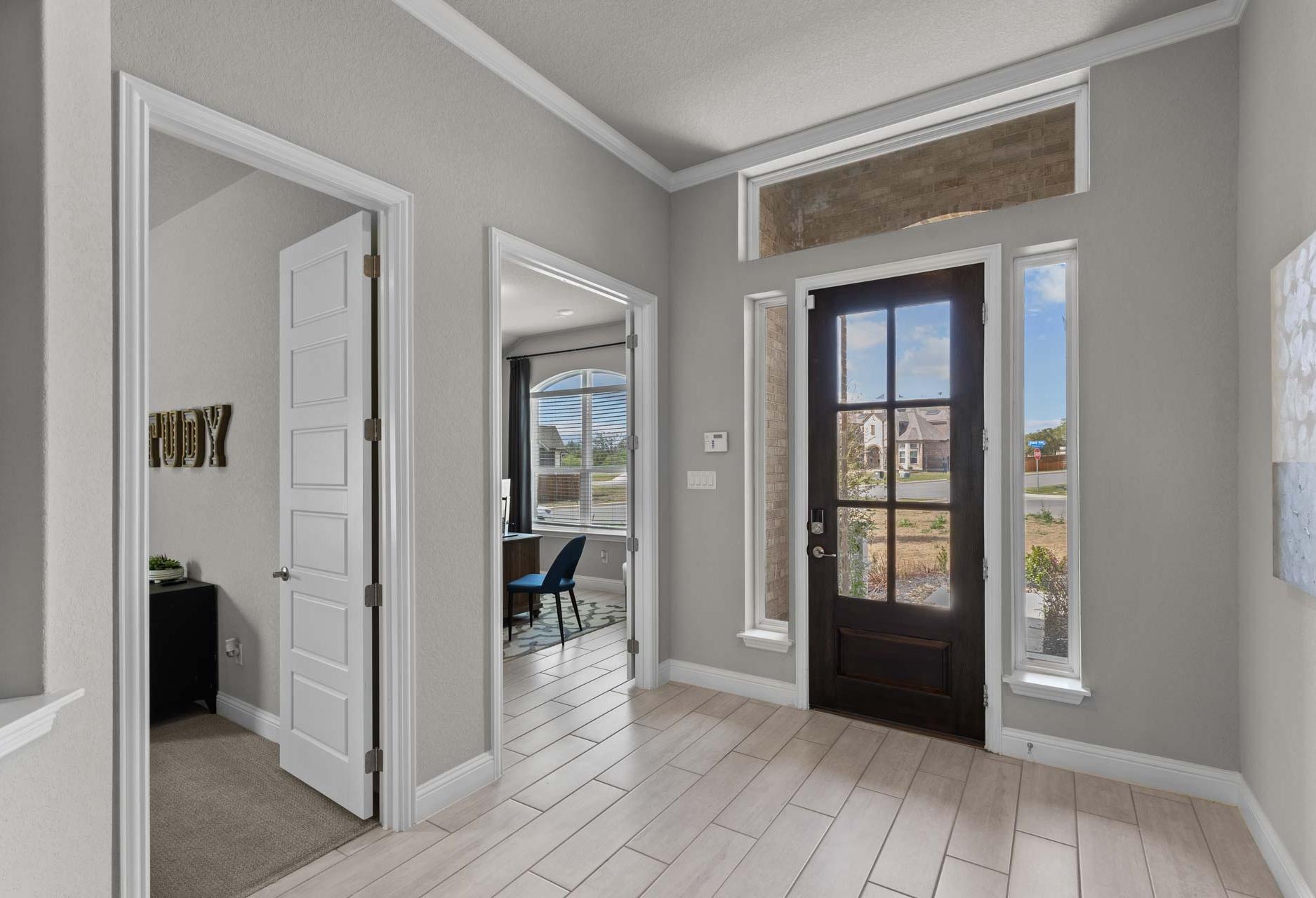 Spacious foyer in The Garner A home with open study doorway, wooden front door, and tile flooring