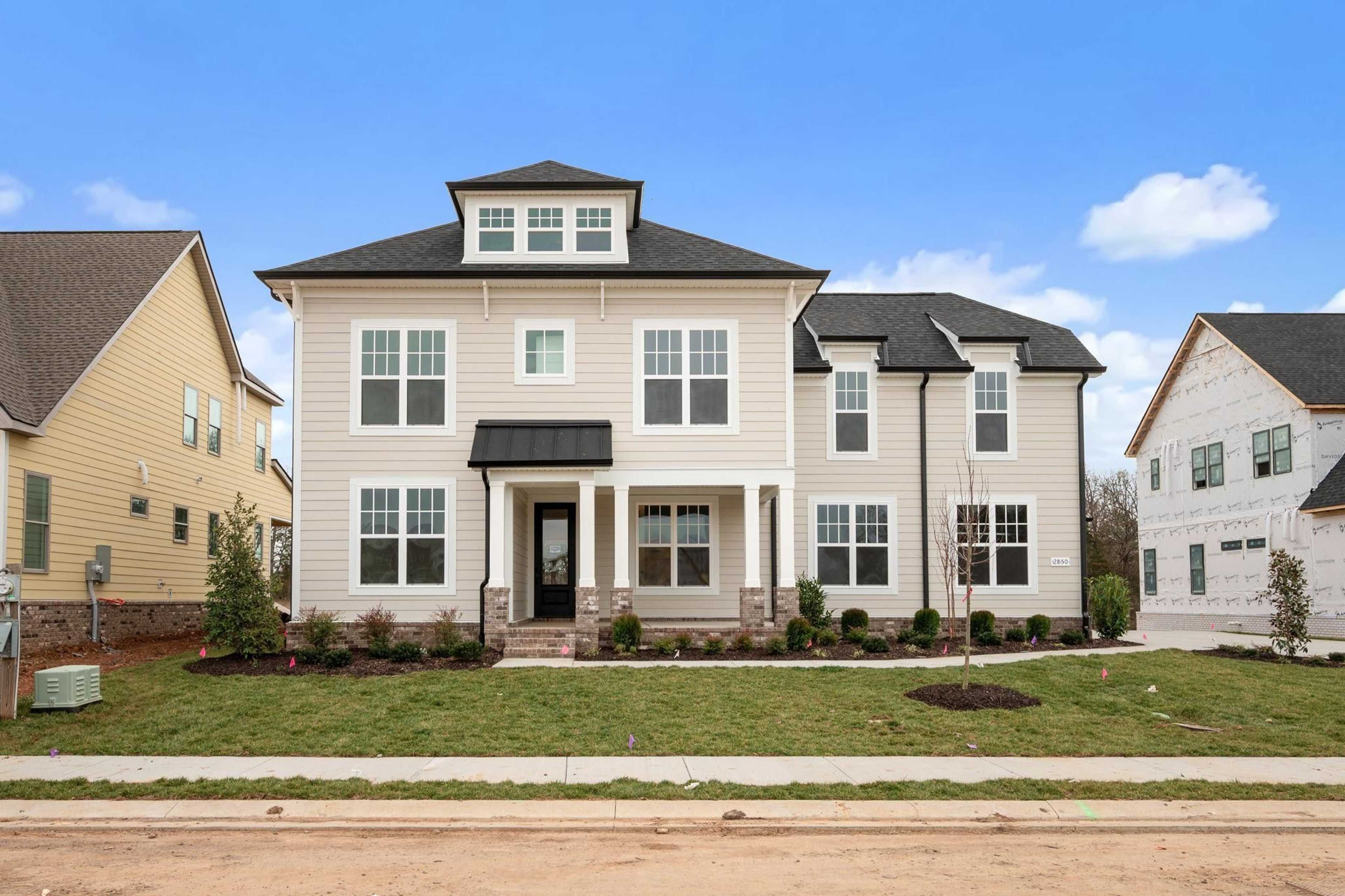 Contemporary two-story homes at Shelton Square in Murfreesboro TN with beige siding, black roofs, covered porches, and landscaped yards