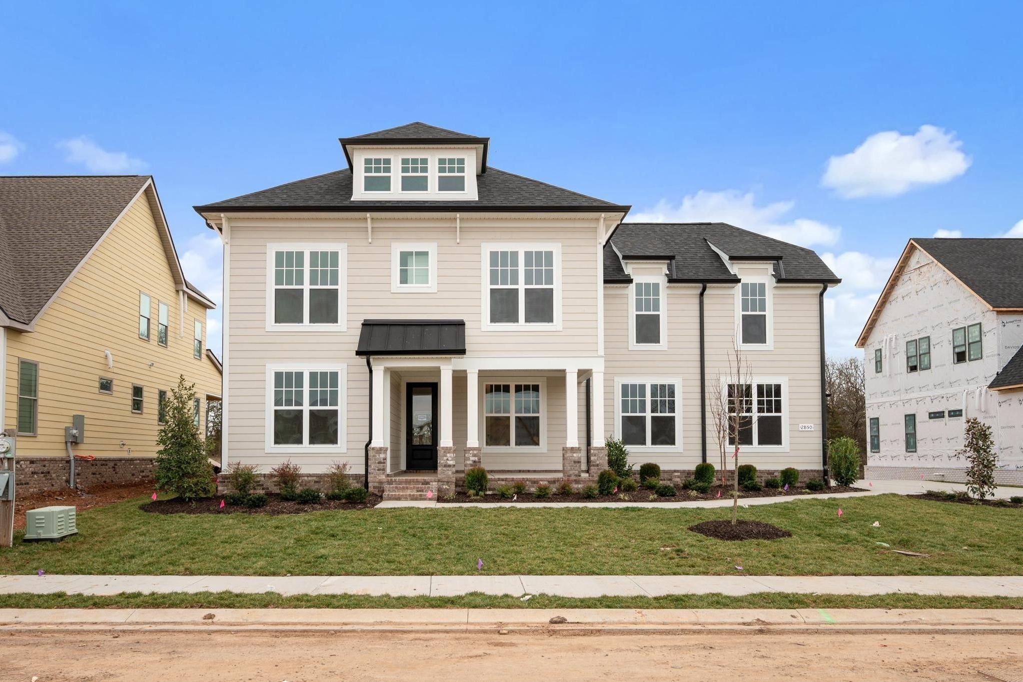 Contemporary two-story homes at Shelton Square in Murfreesboro TN with beige siding, black roofs, covered porches, and landscaped yards
