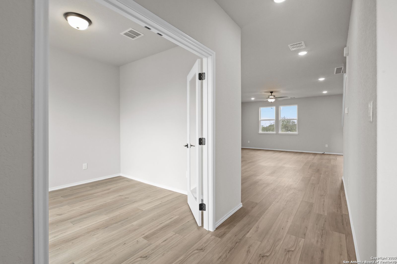 Bright home office with open door to spacious living area, wood laminate floors, ceiling fan in Davidson Homes Murray J, San Antonio
