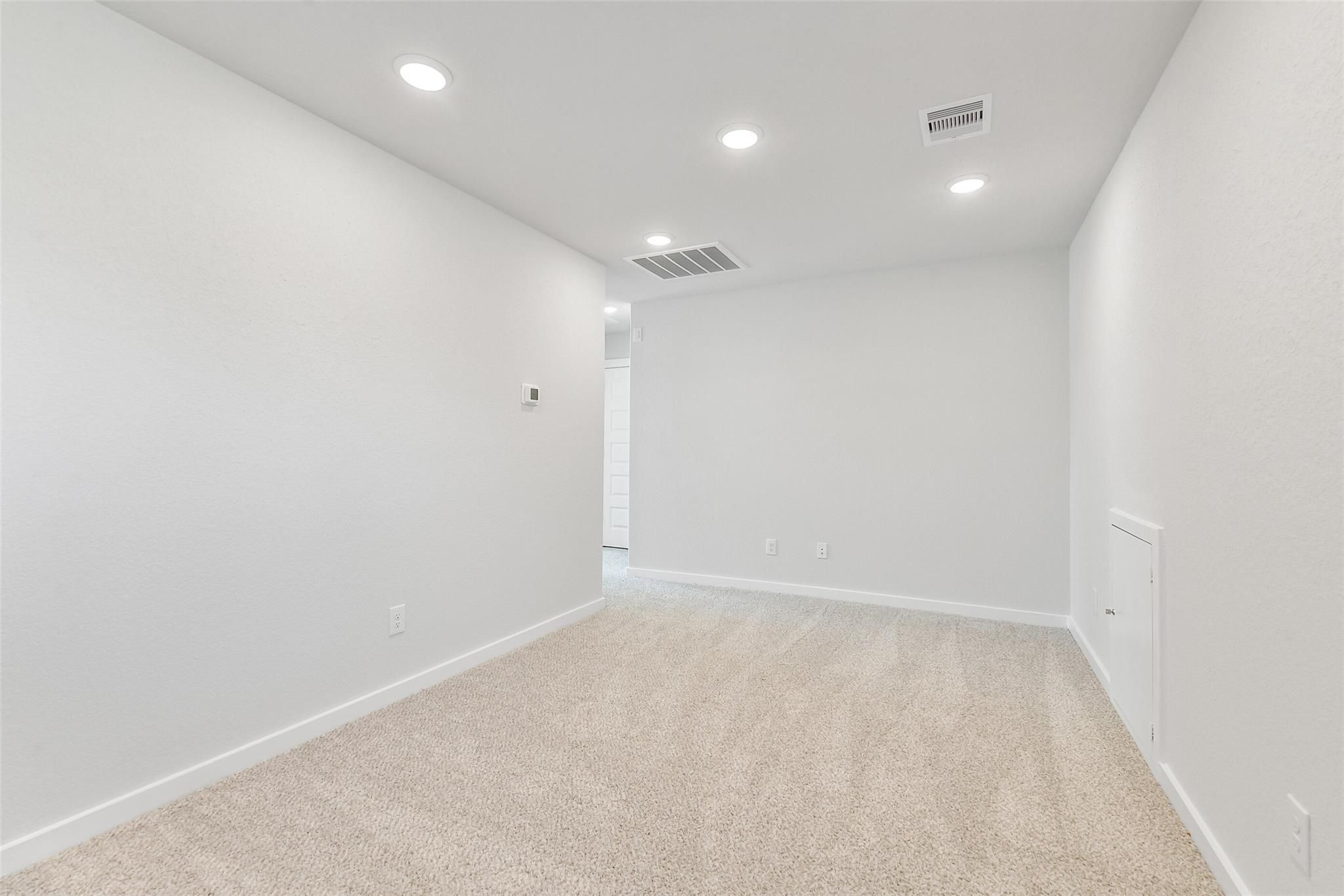 Spacious empty bedroom with white walls, recessed lighting, beige carpet in Davidson Homes Blanco E, Magnolia, Texas